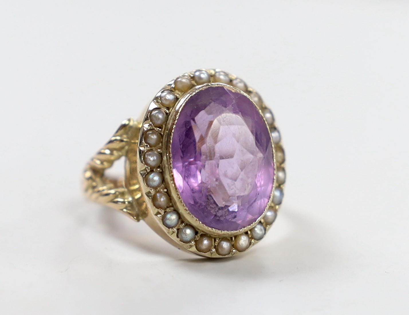 A Victorian style yellow metal, amethyst and seed pearl set oval dress ring, size N/O, gross weight 6.3 grams.                                                                                                              