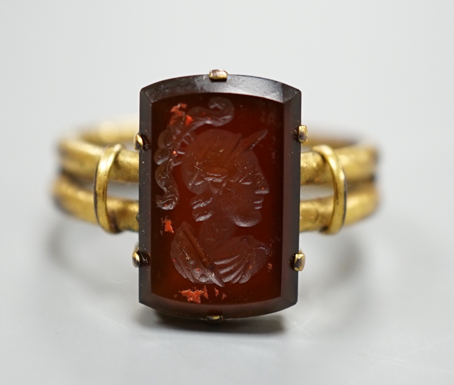 A 19th century yellow metal overlaid and rectangular intaglio chalcedony set ring, the matrix carved with the bust of a Roman soldier to sinister, size O, gross weight 2.7 grams.                                          