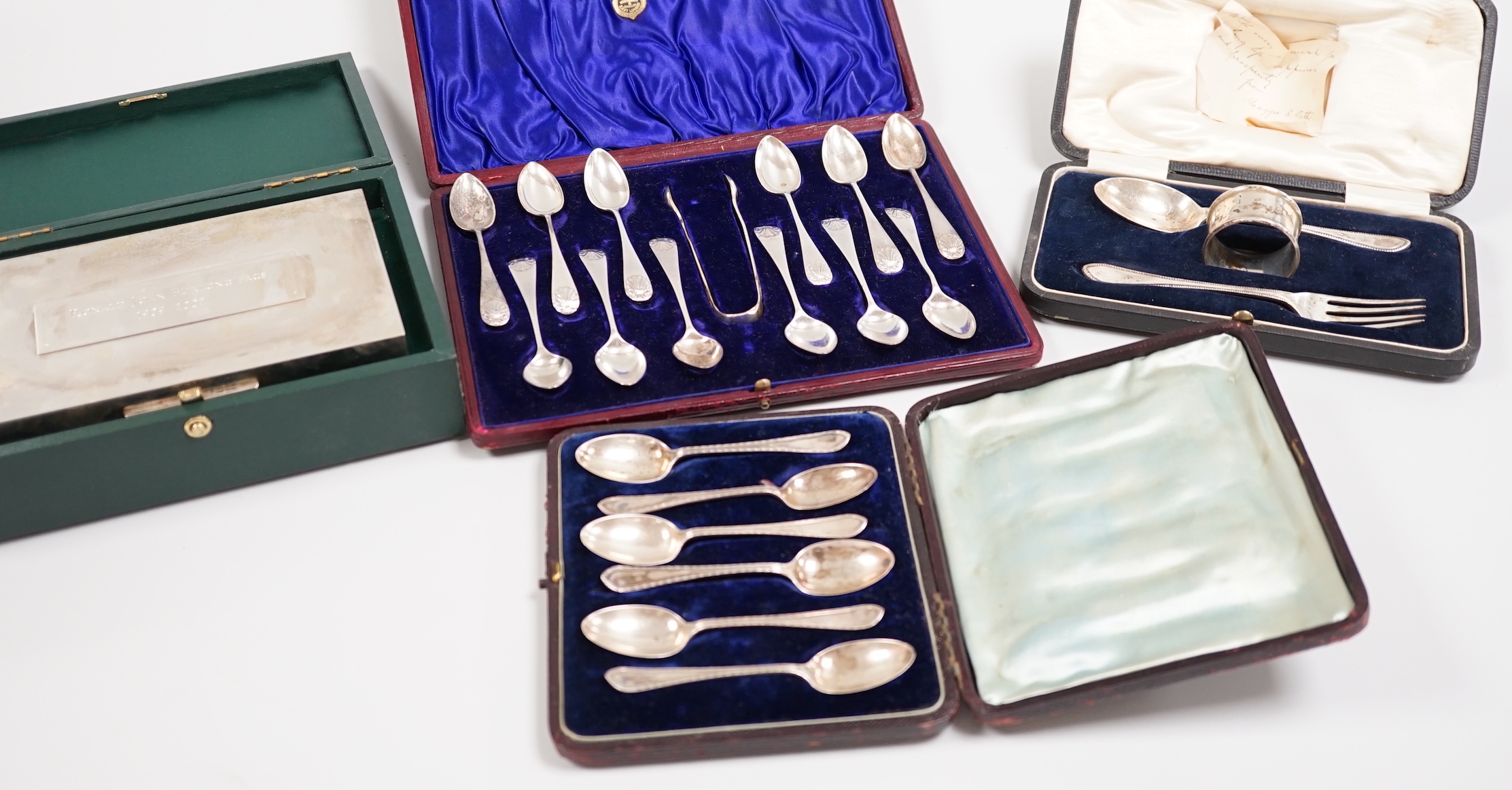 A cased George V silver christening trio, two cased sets of silver teaspoons, including set of twelve with sugar tongs and a cased modern silver mounted presentation cigarette box.                                        