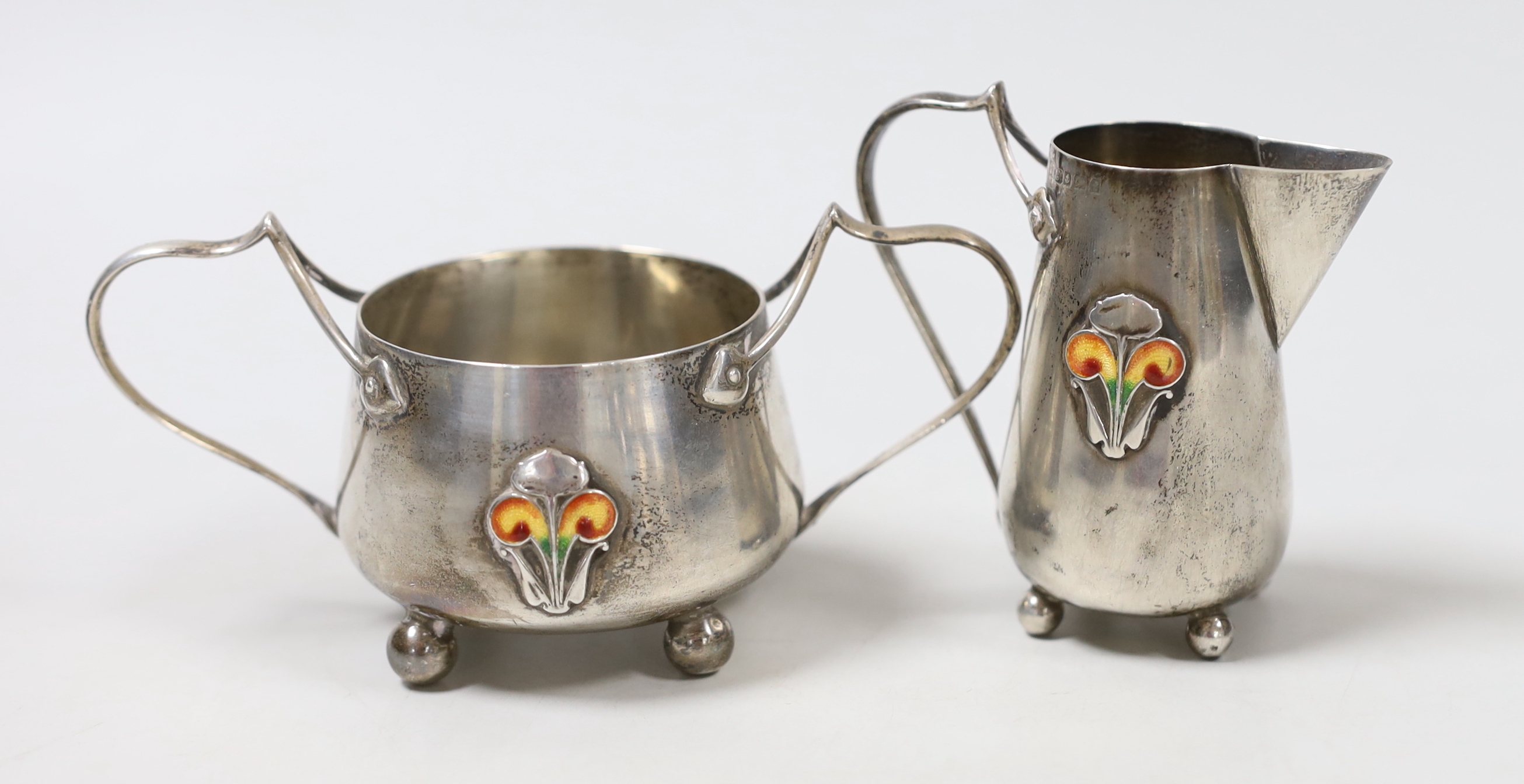 An Edwardian Art Nouveau silver and enamelled cream jug and sugar bowl, C & Co, Birmingham, 1905, jug height 76mm, gross weight 123 grams.                                                                                  