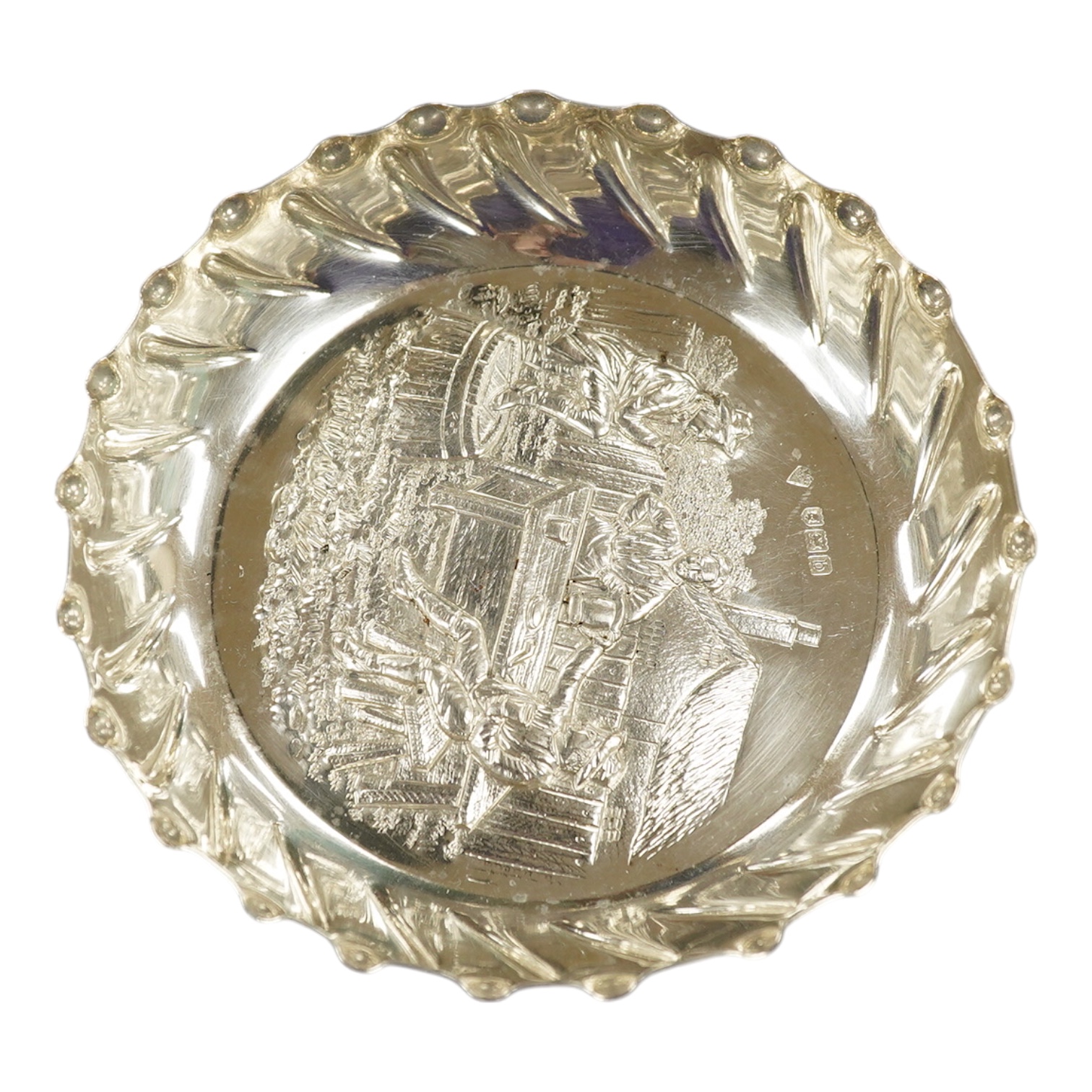 A late Victorian silver shallow dish embossed with imbibers, Mappin Brothers, London, 1897, 13.5cm, 3.8oz. Condition - good                                                                                                 