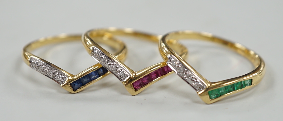 A set of three 750, sapphire, emerald and diamond set wishbone rings, (to be worn as one or singularly), size M/N, gross weight 5.4 grams.                                                                                  