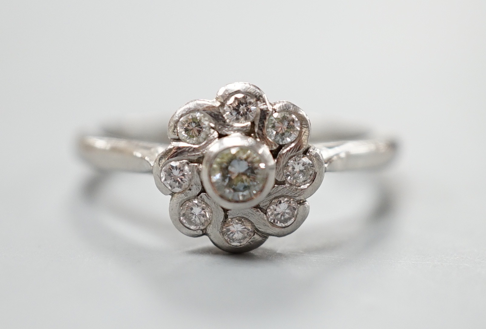 A modern platinum and nine stone diamond set flower head cluster ring, size O, gross weight 5.4 grams.                                                                                                                      