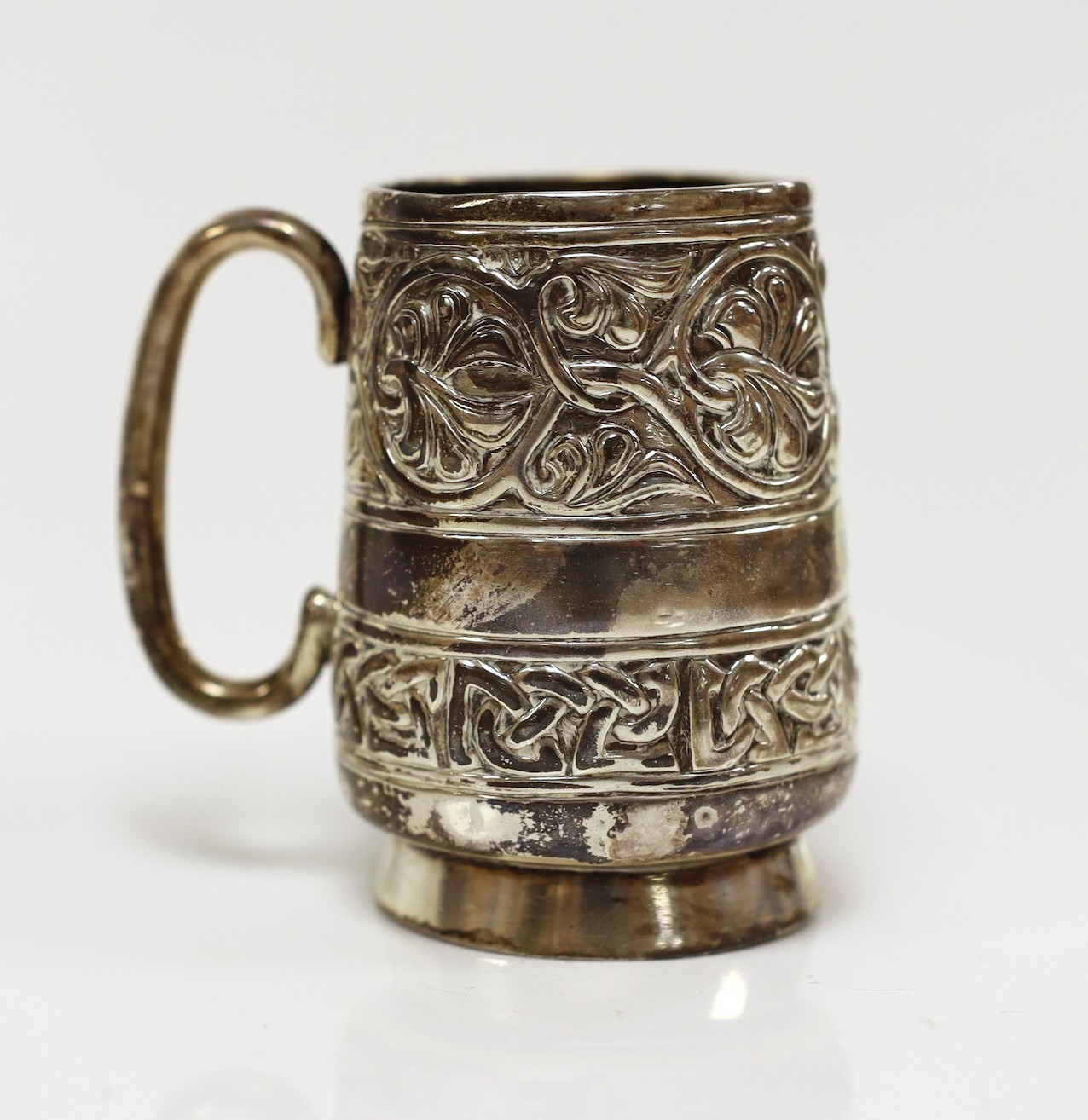 A George V embossed silver Iona mug, by Alexander Ritchie, Chester, 1911, with engraved initials, height 86mm, 1018 grams.                                                                                                  