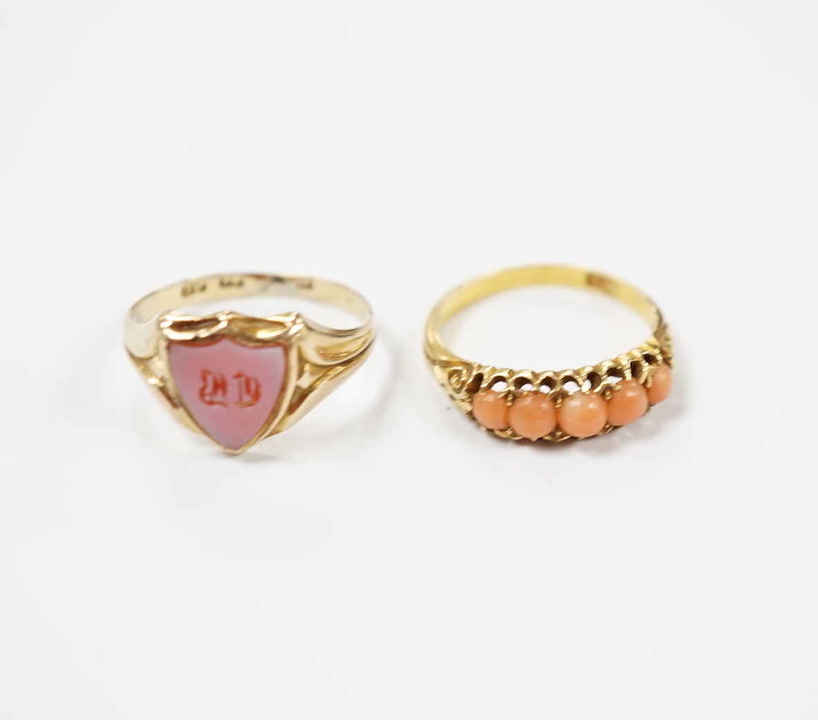 An early 20th century 18ct and graduated five stone split coral bead set half hoop ring, size O and a Victorian 12ct gold and sardonyx set shield shaped signet ring, size Q.                                               