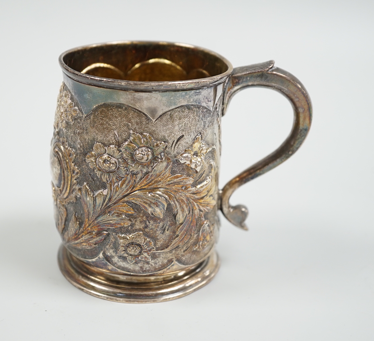 A George II silver mug, with later embossed decoration, makers mark rubbed, London, 1724, 9cm, (a.f.) 6.1oz.                                                                                                                
