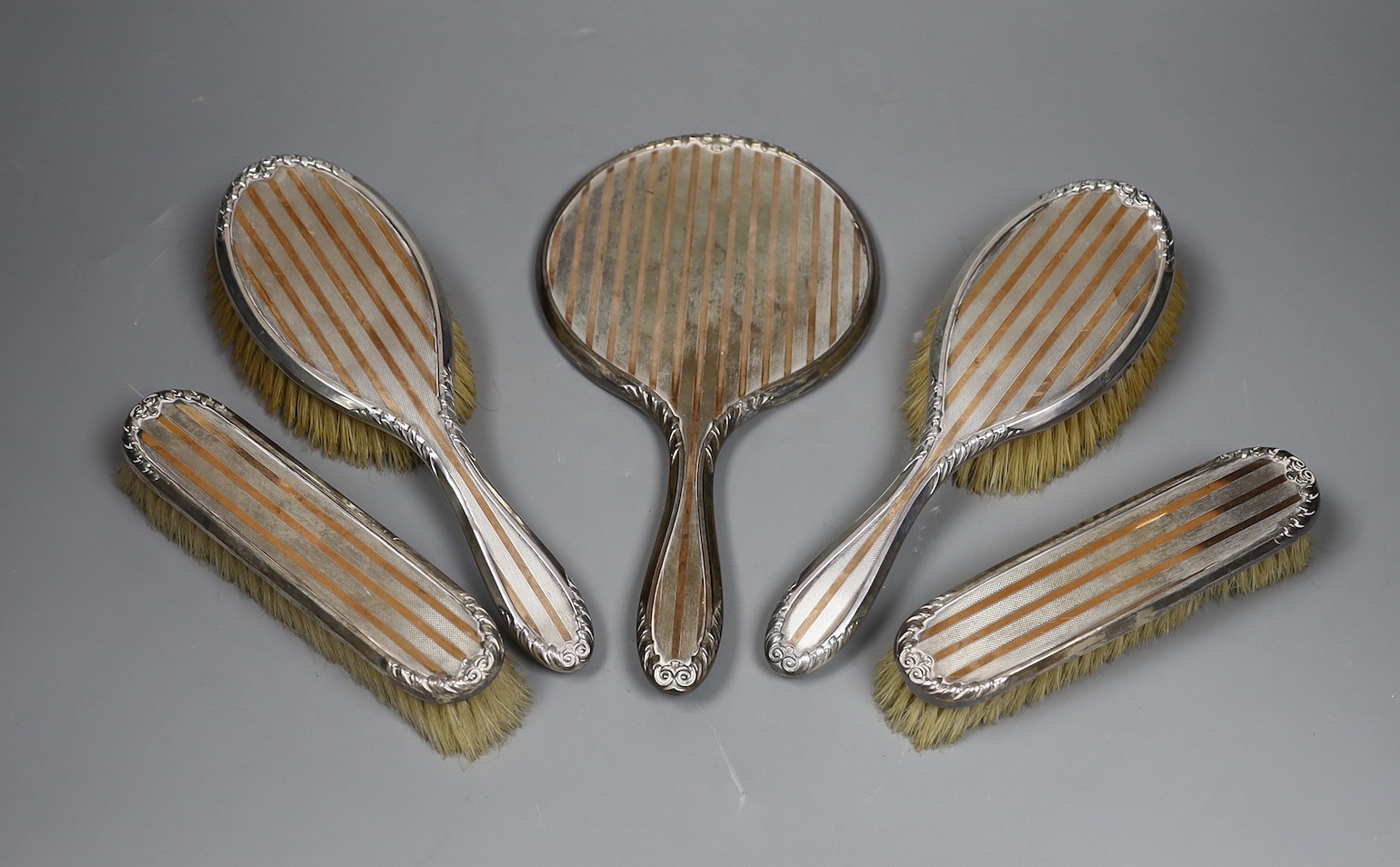 A George V silver and yellow metal five piece dressing table mirror and brush set, by Charles & Richard Comyns, London, 1924.                                                                                               