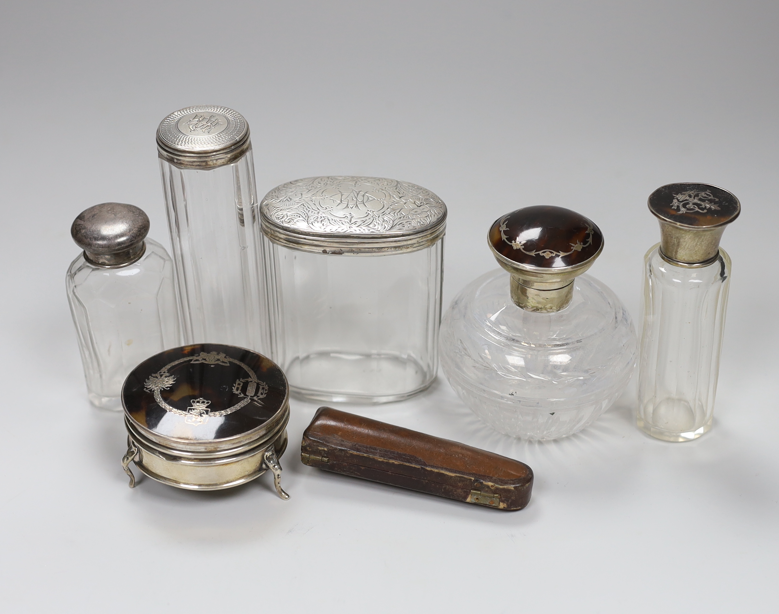 A George V tortoiseshell pique and silver trinket casket, 6cm, two tortoiseshell pique mounted glass jars, three further silver mounted glass toilet jars and a cased cigar holder                                          