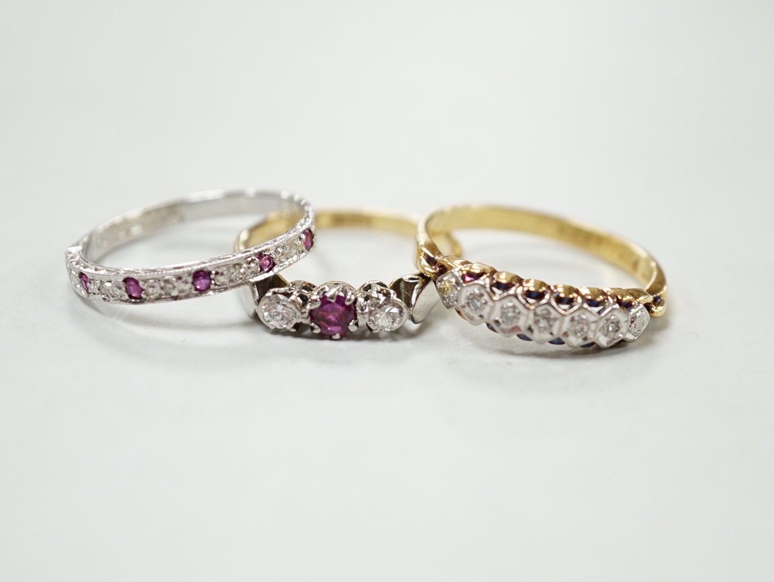 A modern 18ct gold, ruby and diamond chip set half eternity ring, size O and two 18ct & plat rings including illusion set diamond half hoop, gross weight 7.5 grams.                                                        