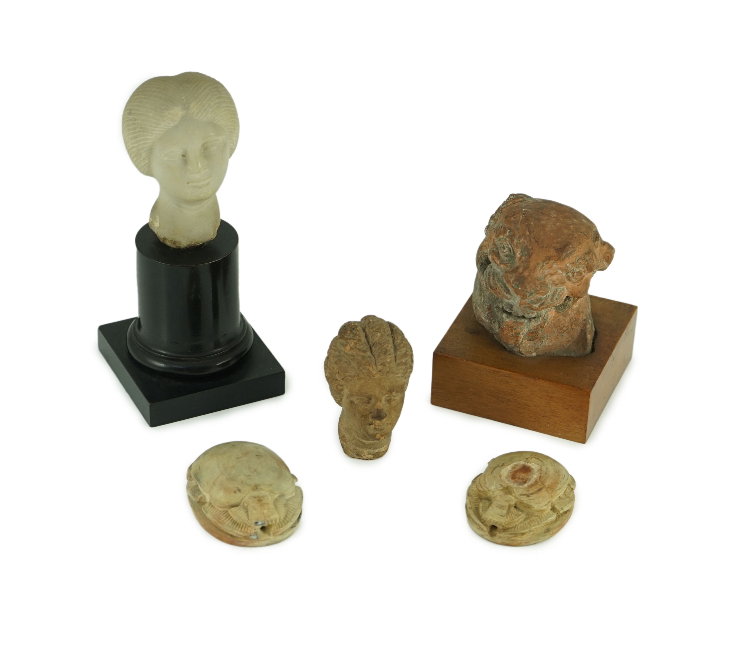 A group of antiquities comprising two commemorative scarabs, an Egyptian style gypsum head, and two antique terracotta heads                                                                                                