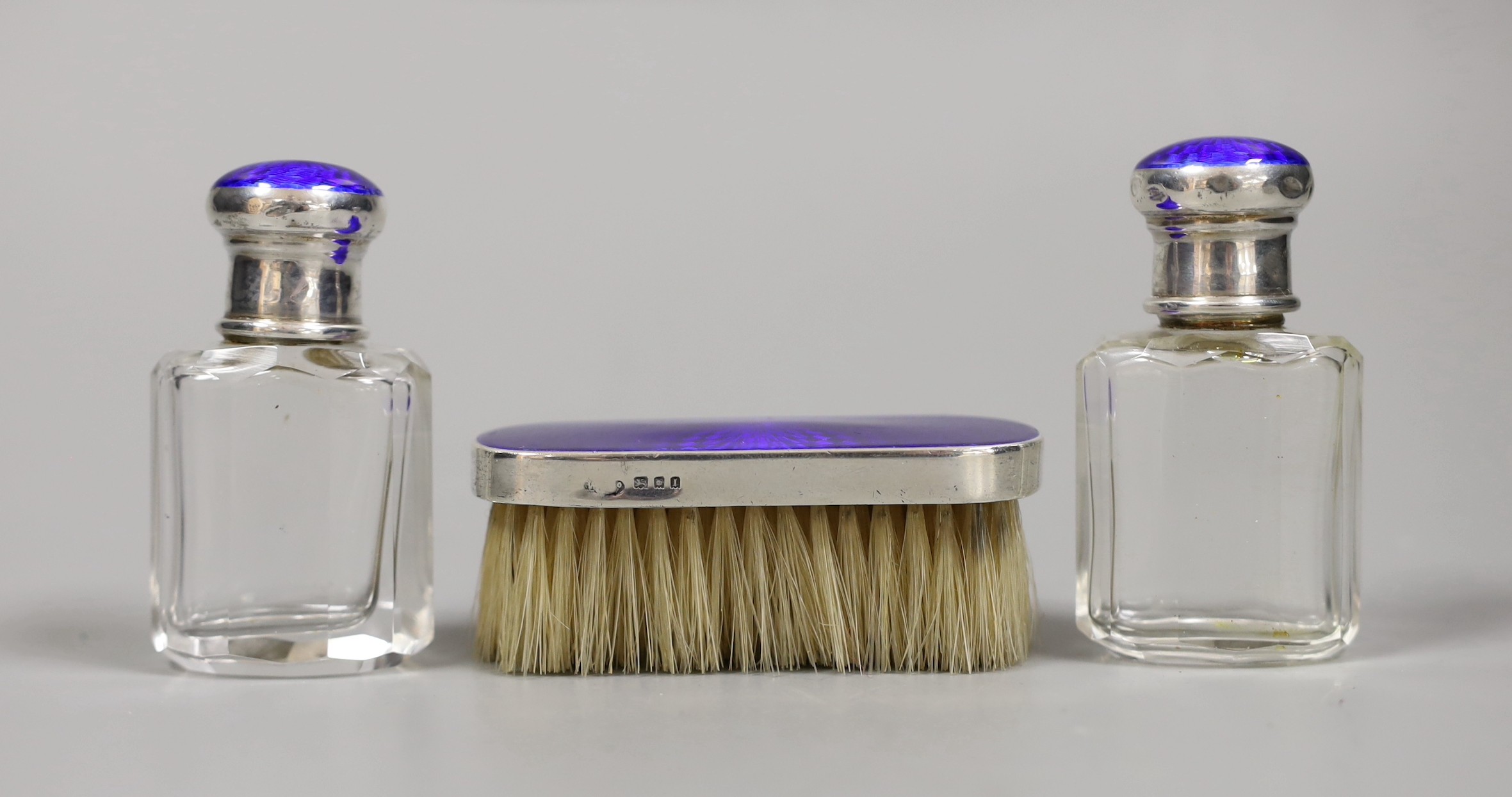 A pair of George V silver and enamel mounted glass scent bottles, 73mm and a small mounted brush, London, 1926.                                                                                                             