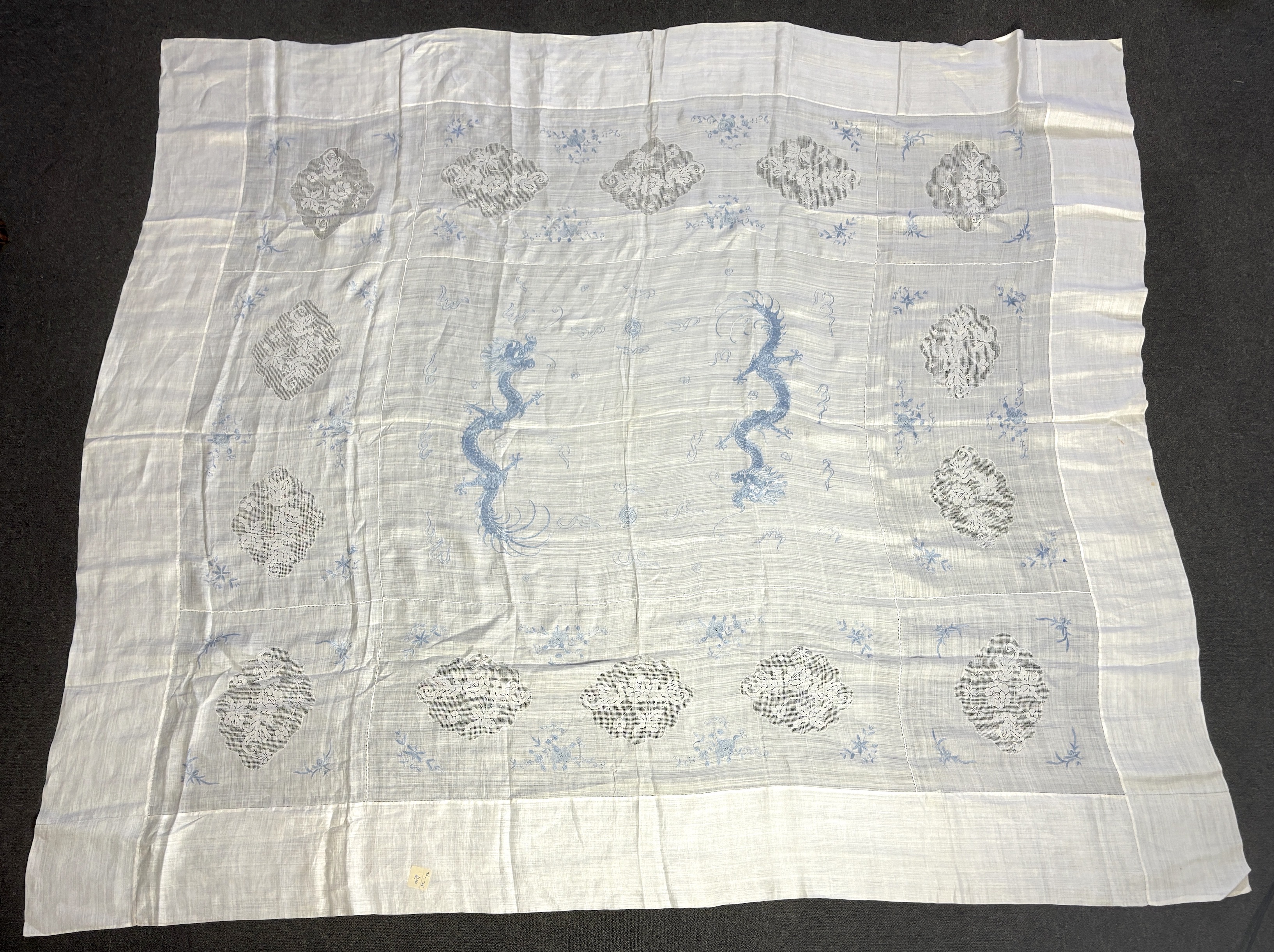 Chinese dragon and floral embroidered linen comprising two Chinese hand embroidered table cloths, both embroidered with blue dragons and flowers, together with a similar embroidered pillow case, a smaller cloth with whit