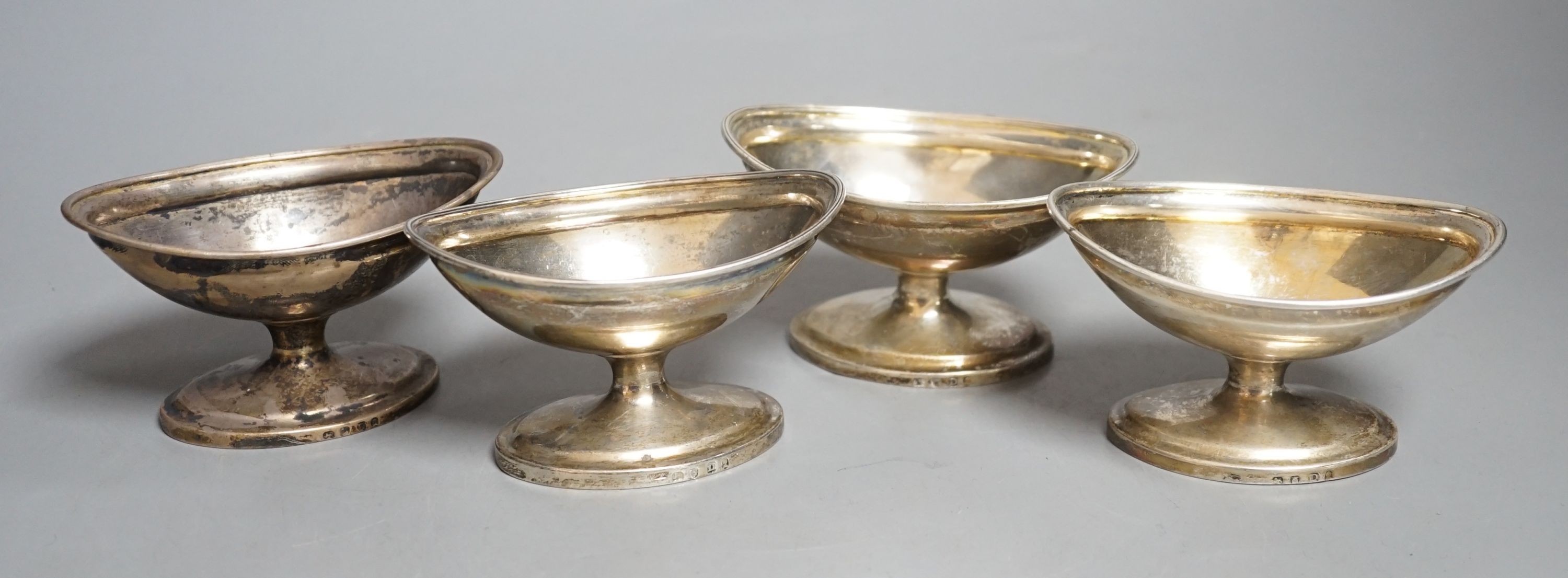 A set of four George III silver boat shaped pedestal salts, London, 1799, maker's mark rubbed, length 10cm, 345 grams.                                                                                                      
