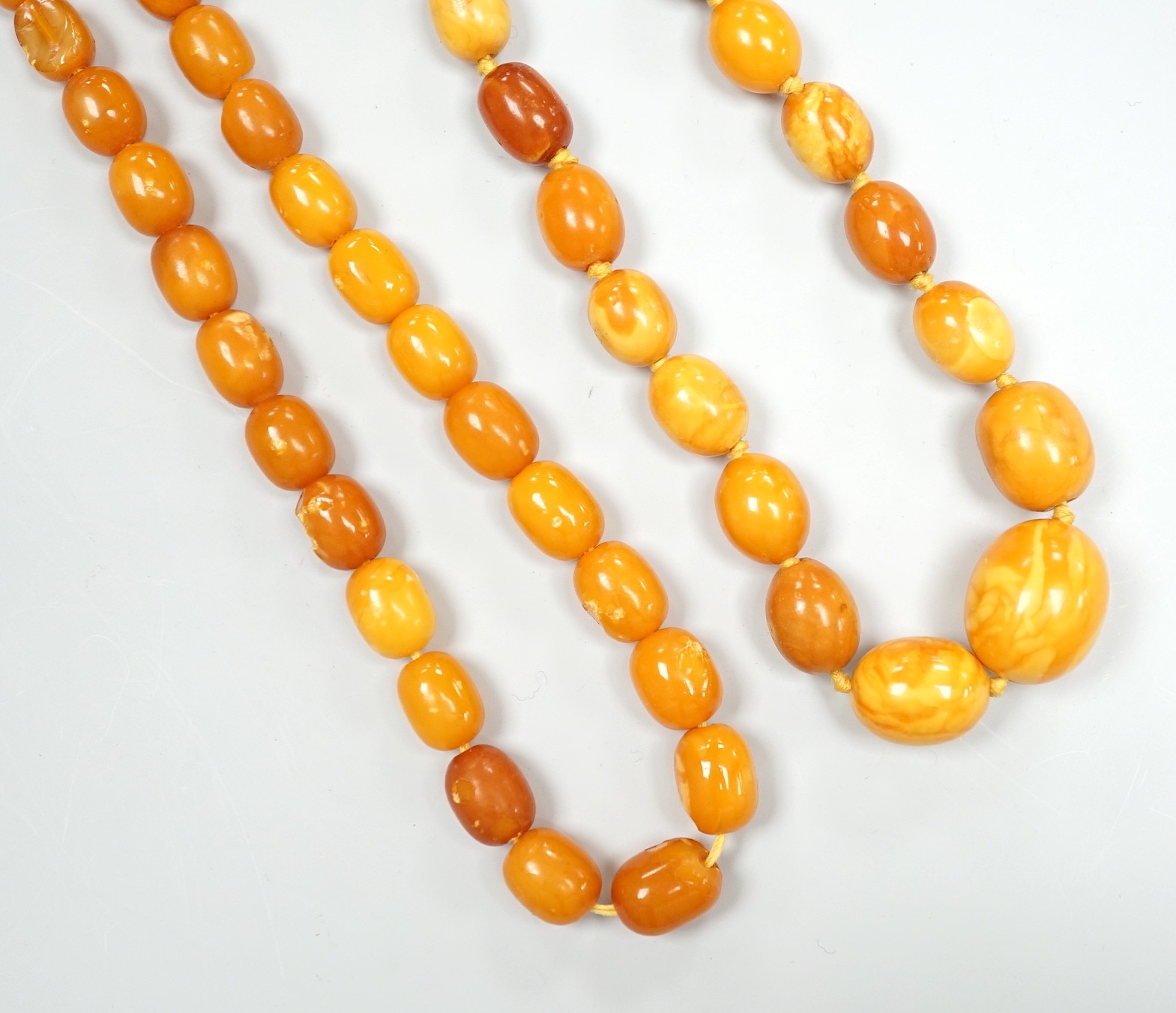 Two single strand graduated oval amber bead necklaces, one a.f., longest 43cm, gross weight 38 grams.                                                                                                                       