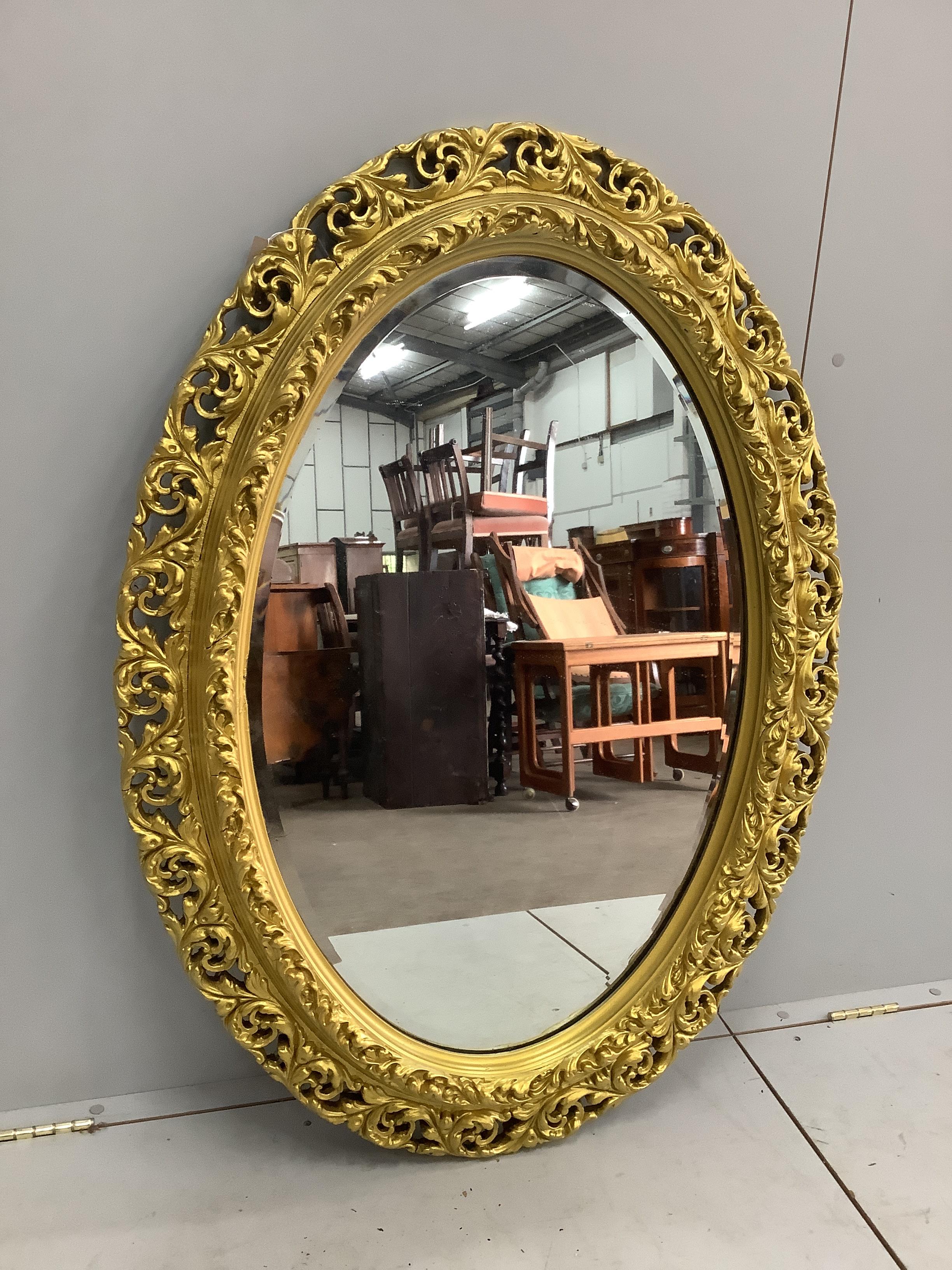 An oval gilt composition wall mirror, width 82cm, height 114cm                                                                                                                                                              