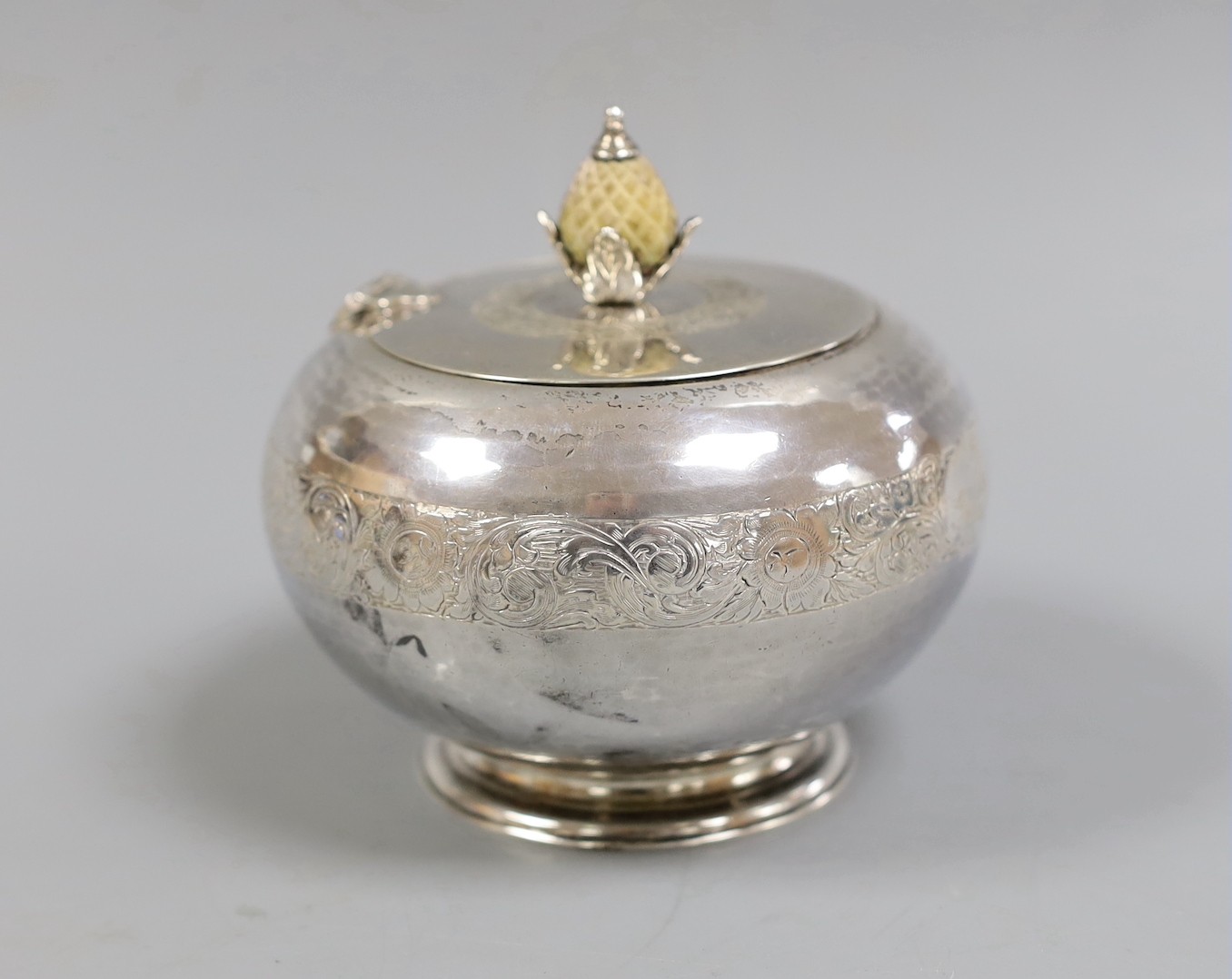 A George V engraved silver globular tea caddy, with carved stained wooden pineapple shaped knop, Goldsmiths & Silversmiths Co Ltd, London, 1920, height 11.3cm, gross weight 12oz.                                          