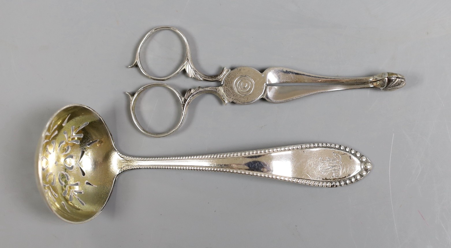 A pair of George III silver sugar nips, George Smith III, London, circa 1780, 11.6cm and a sterling sifter spoon, 2.2oz.                                                                                                    