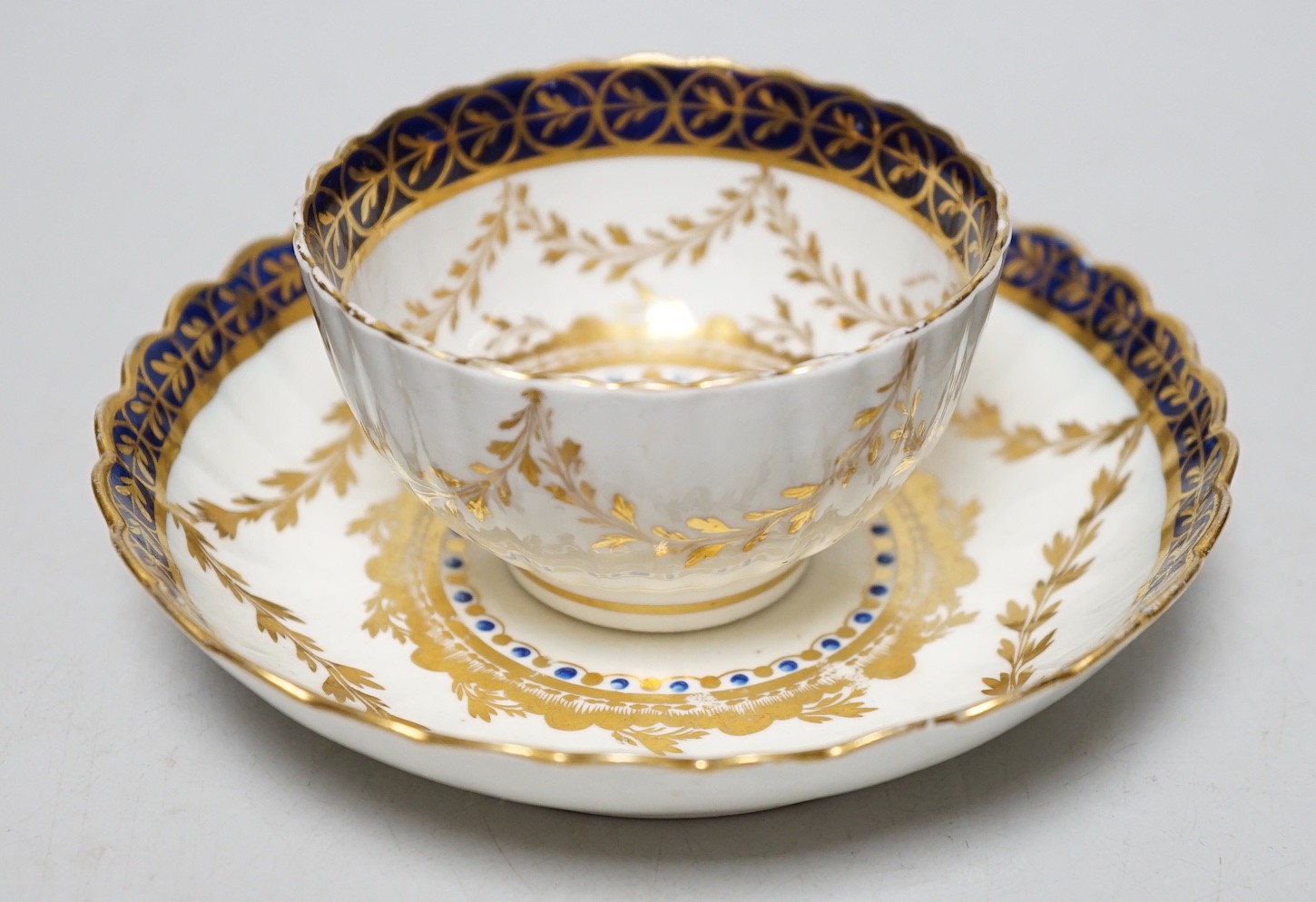 An 18th century Caughley rare teabowl and saucer painted with a crest of an arm clutching a dragon en-circled by three gilt borders. 6cm tall overall                                                                       