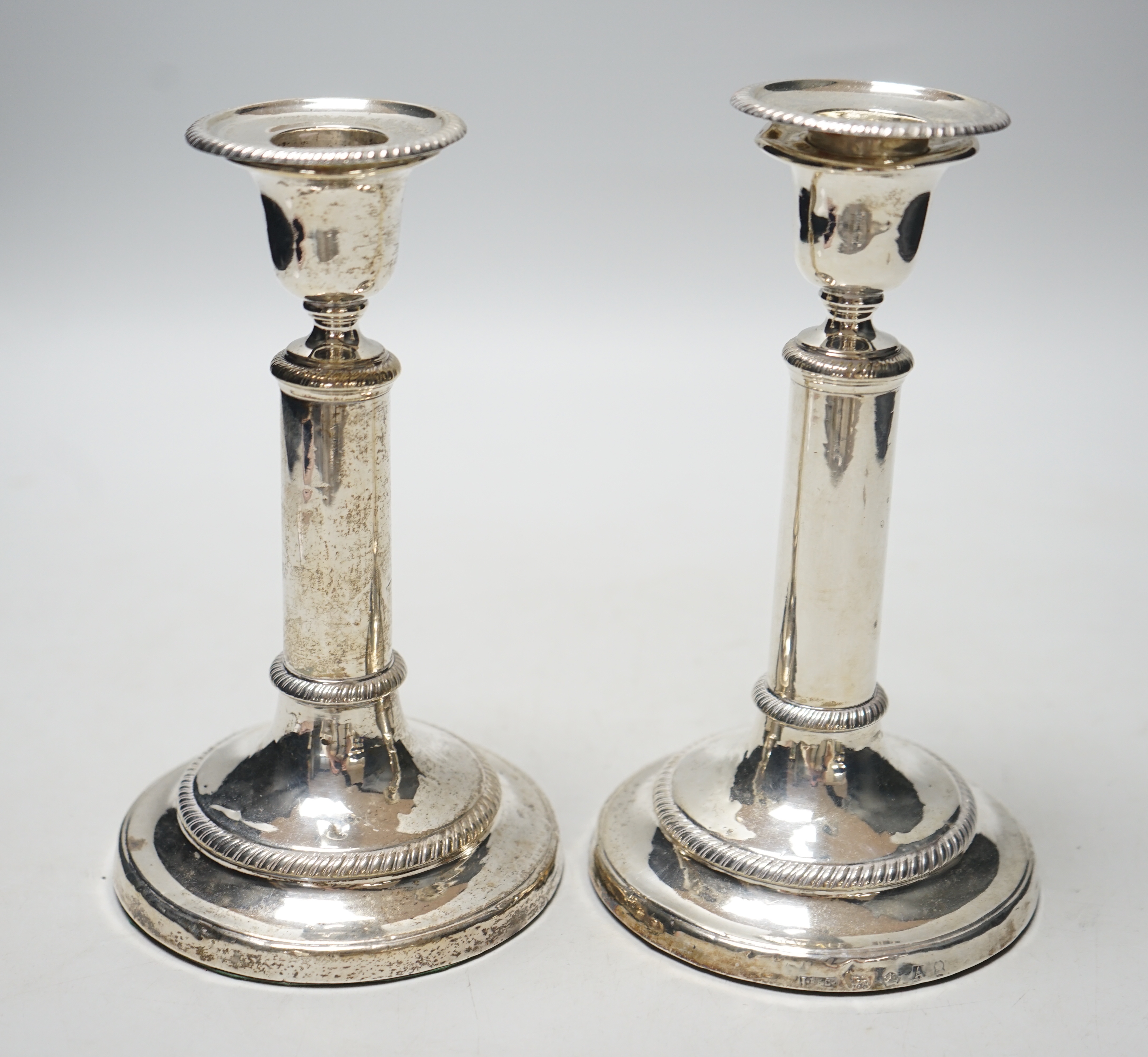 A pair of George III silver candlesticks, with cylindrical stems, John Roberts & Co, Sheffield, 1806, 18.3cm, weighted, (a.f.).                                                                                             