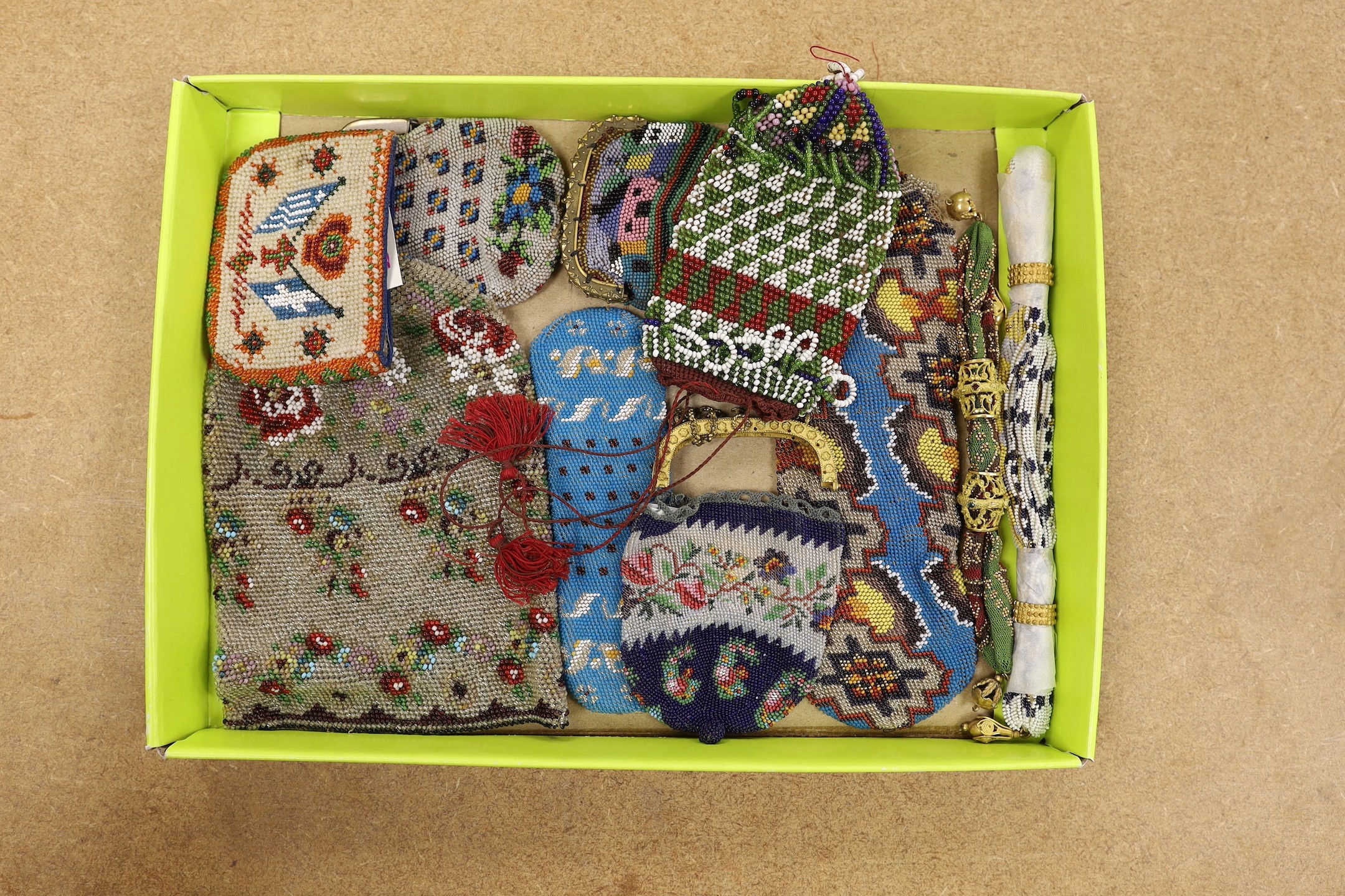 An unusual early 19th century cut steel misers purse with ornate jewelled gilt metal bands, another similar purse, two other brightly beaded misers purses and a further quantity of metal framed beadwork purses and a bag 