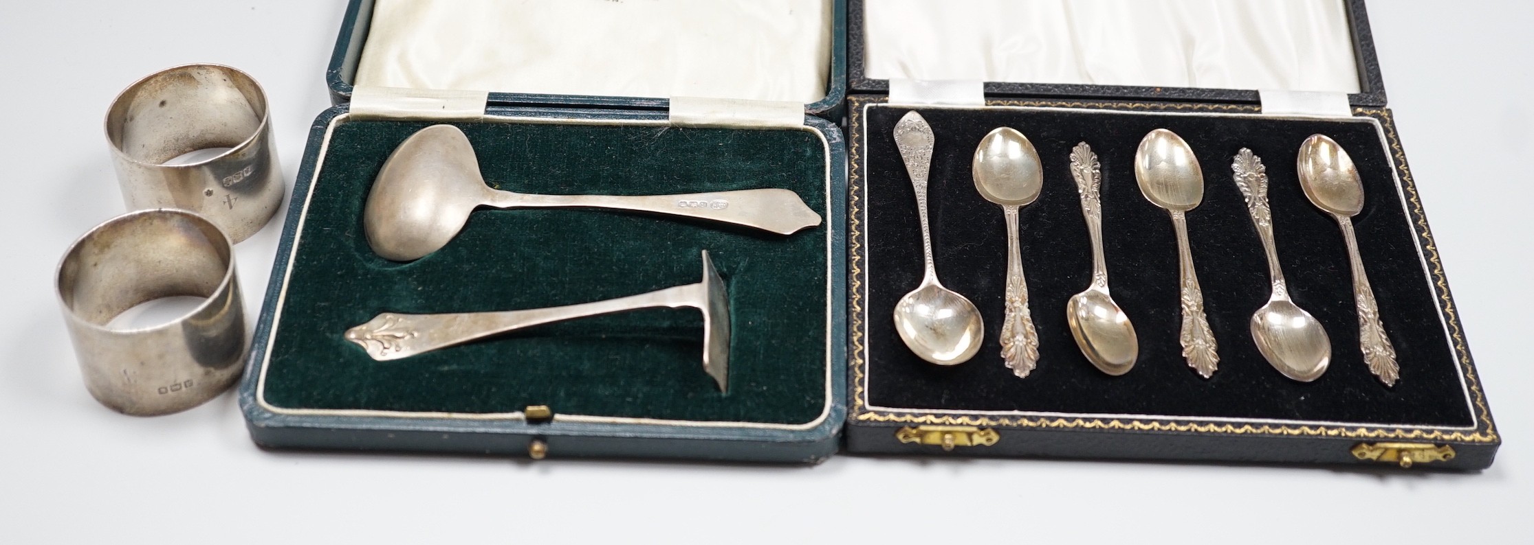 A pair of George V silver napkin rings, Edward Barnard & Sons Ltd, London, 1916 and two cased sets of silver cutlery, coffee spoons and spoon and pusher.                                                                   