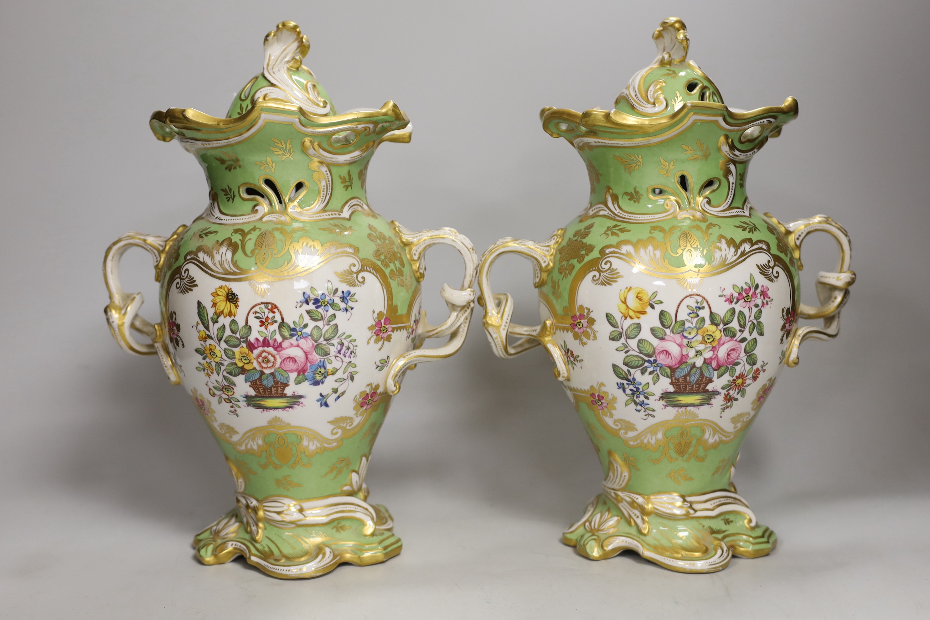 AMENDED DESCRIPTION A pair of Rockingham style porcelain pot pourri vases, each of rococo form painted to each side with baskets of flowers, rare brown printed Rockingham griffin mark, 29cm high                          