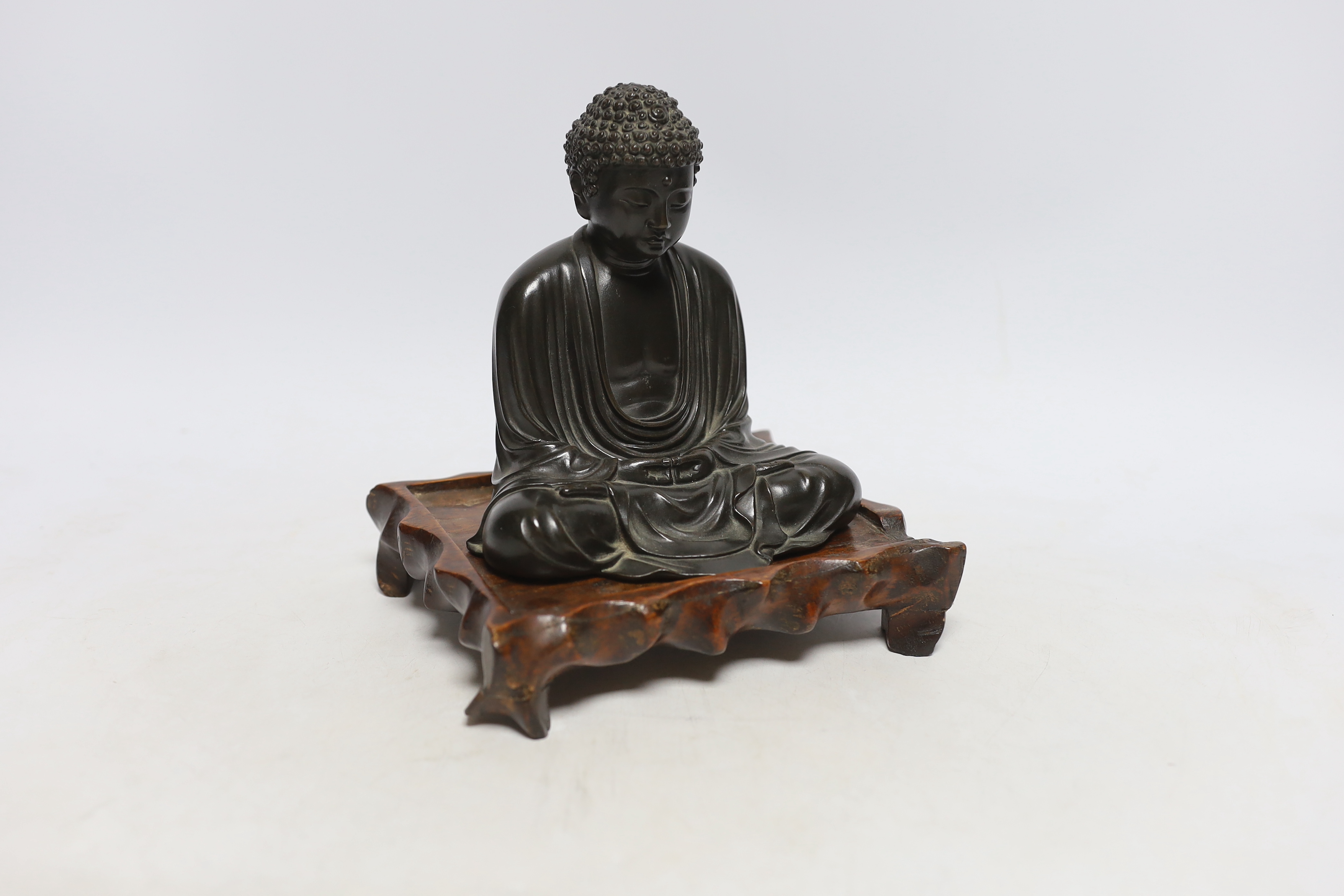 A Japanese bronze figure of Buddha, Meiji period, inscribed seven character mark to base, on a hardwood stand, 15cm high                                                                                                    