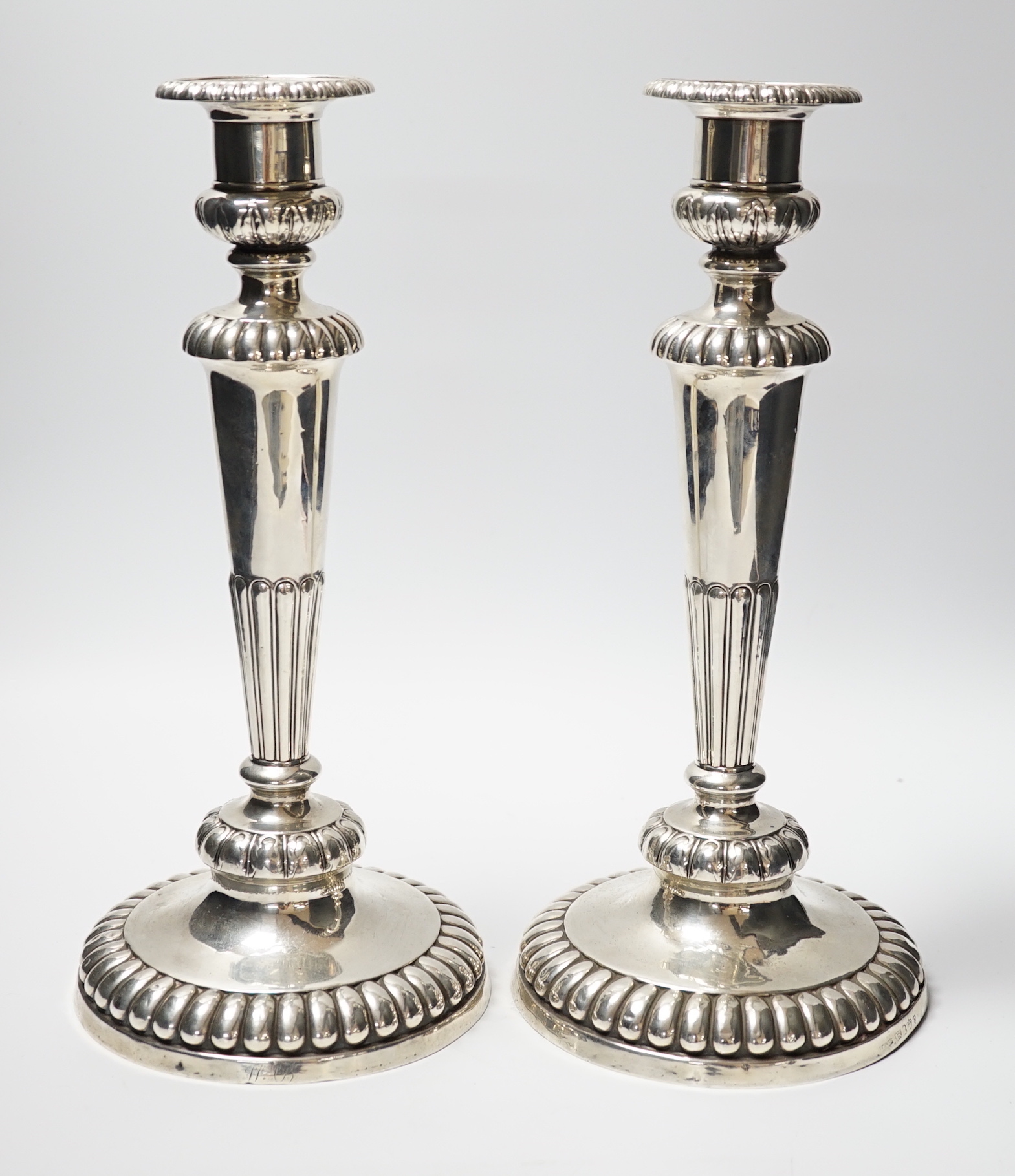 A pair of George III silver candlesticks, on fluted waisted stems, John Roberts & Co, Sheffield, 1811, height 31.6cm, weighted.                                                                                             