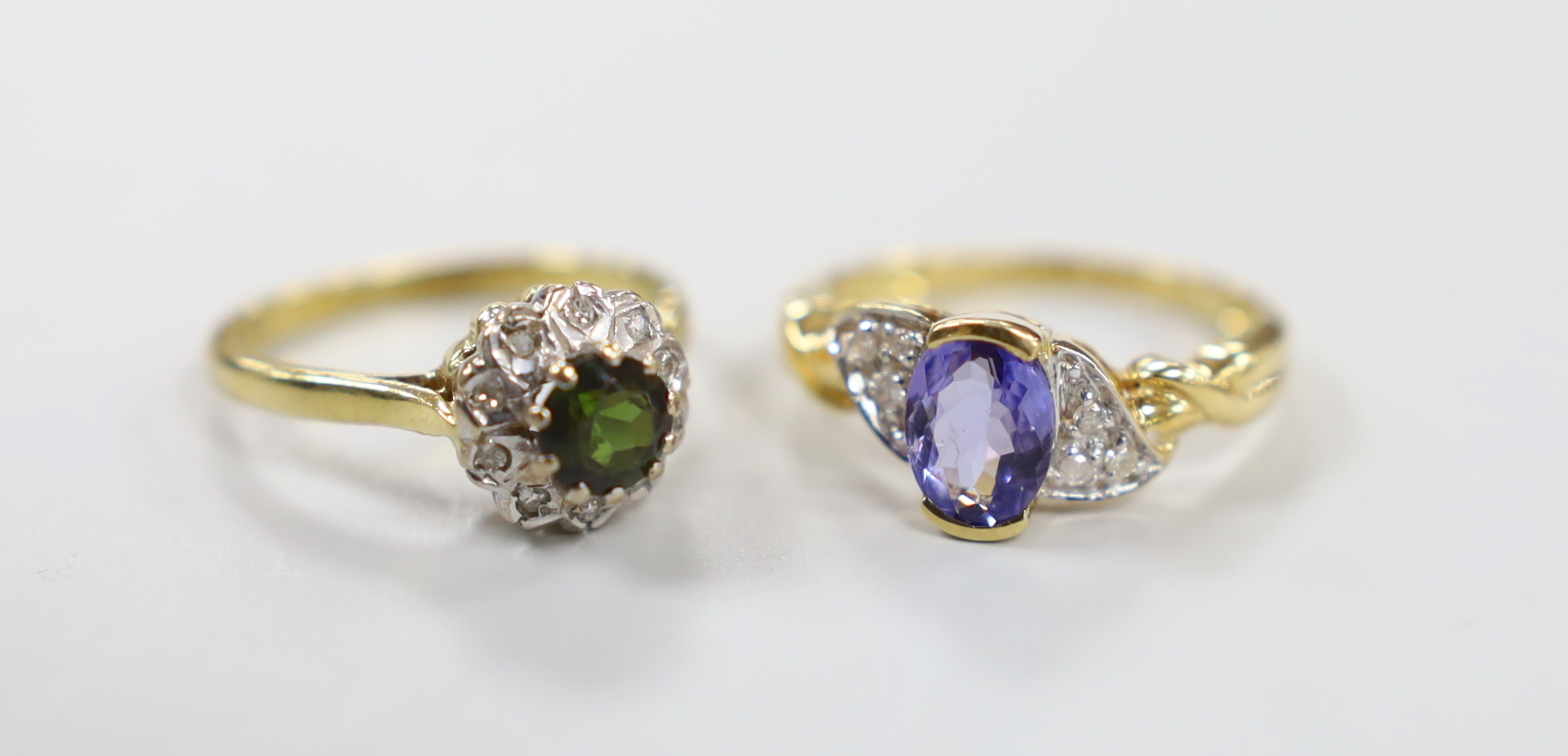 A modern 18ct gold and single stone oval cut tanzanite and diamond chip set cluster dress ring, size P and one other 18ct gold and gem set cluster ring, gross weight 7.9 grams.                                            