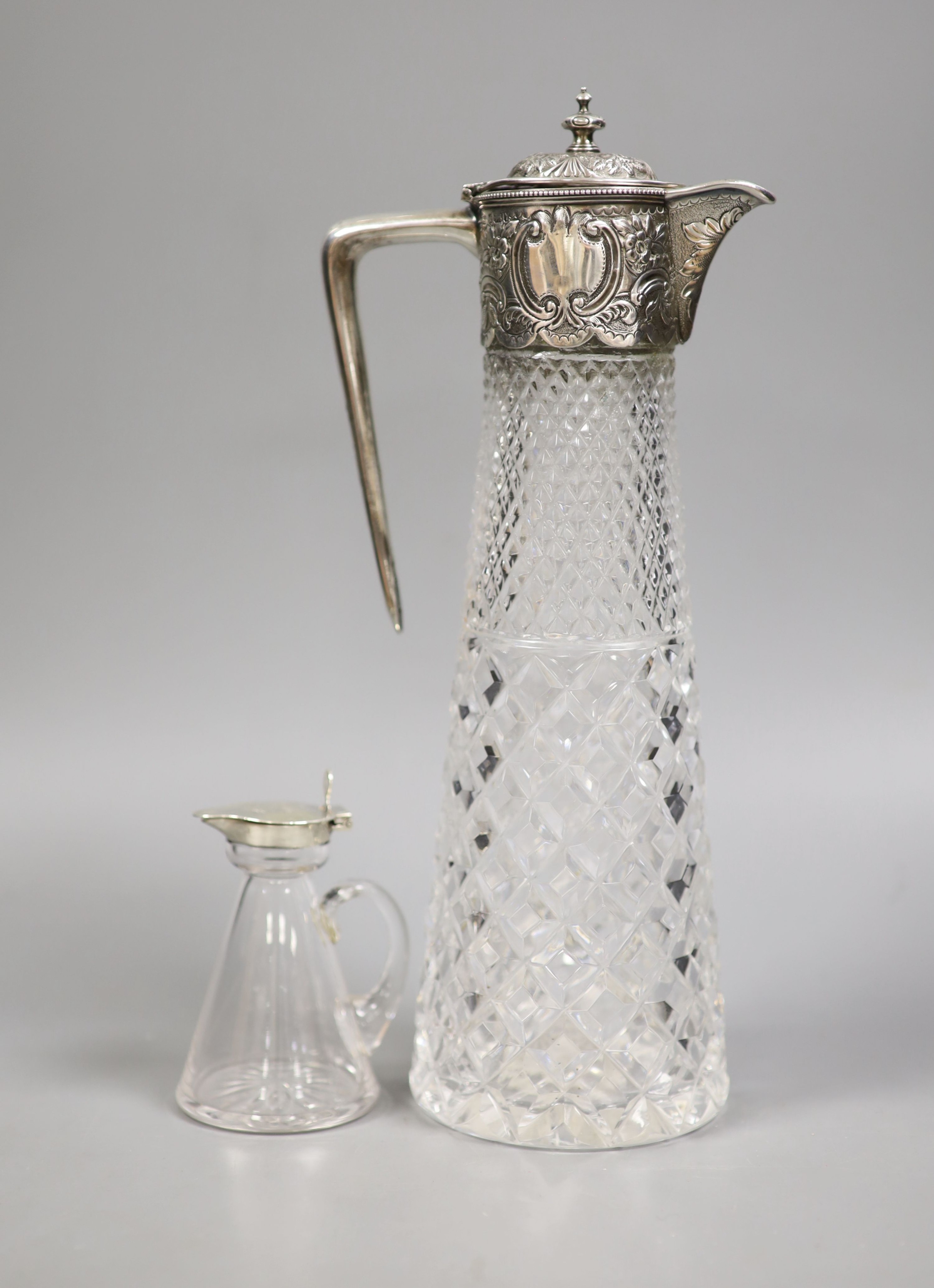 A late Victorian silver mounted cut glass claret jug, Atkin Bros. Sheffield, 1891, 29.4cm and a George V silver mounted glass whisky tot jug.                                                                               