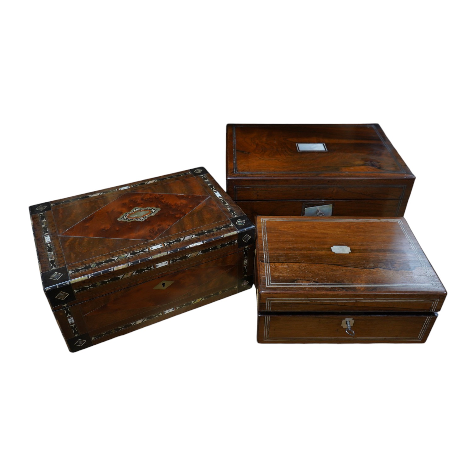 Three 19th century vanity and sewing boxes with fitted interiors to include a mother of pearl inlaid example with glass bottles, jars and mirror, largest 35cm wide. Condition - fair, some losses                          