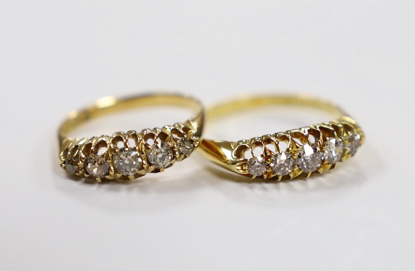 A late Victorian 18ct gold and graduated five stone diamond set half hoop ring, size M/N and an similar Edwardian ring, size R/S, gross weight 6.7 grams.                                                                   