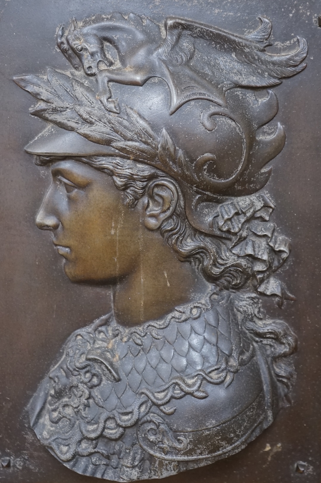 After Edmond Louis Charles Tassel (French, fl. 1870-1900), a bronzed metal bas-relief plaque with the bust of Perseus, mounted on an oak panel, circa 1900. Relief 49.5 cm high x 35cm wide. Condition - poor               