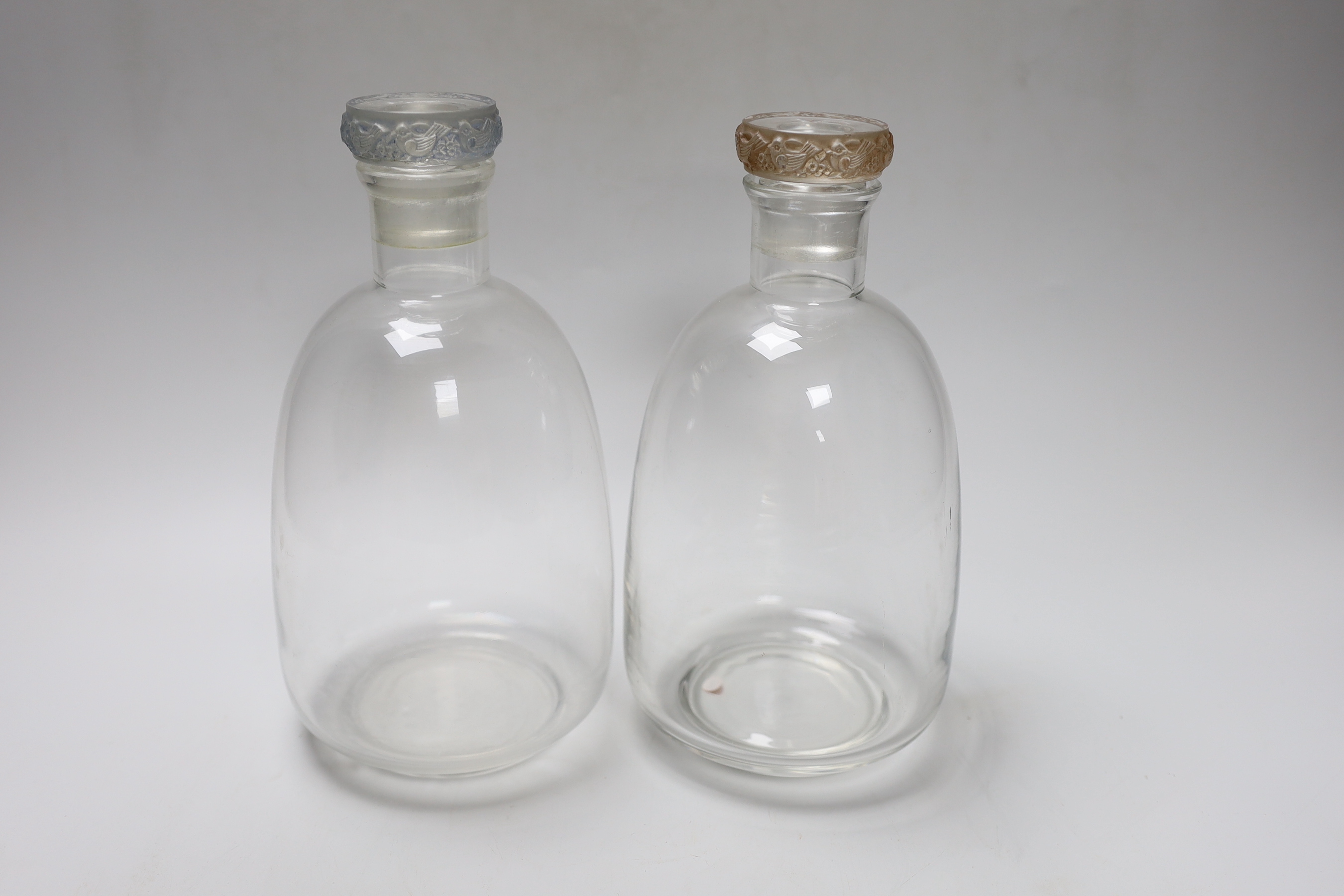 A near pair of Lalique glass decanters, one with blue tinted stopper, the other sepia tinted, 22cm tall                                                                                                                     