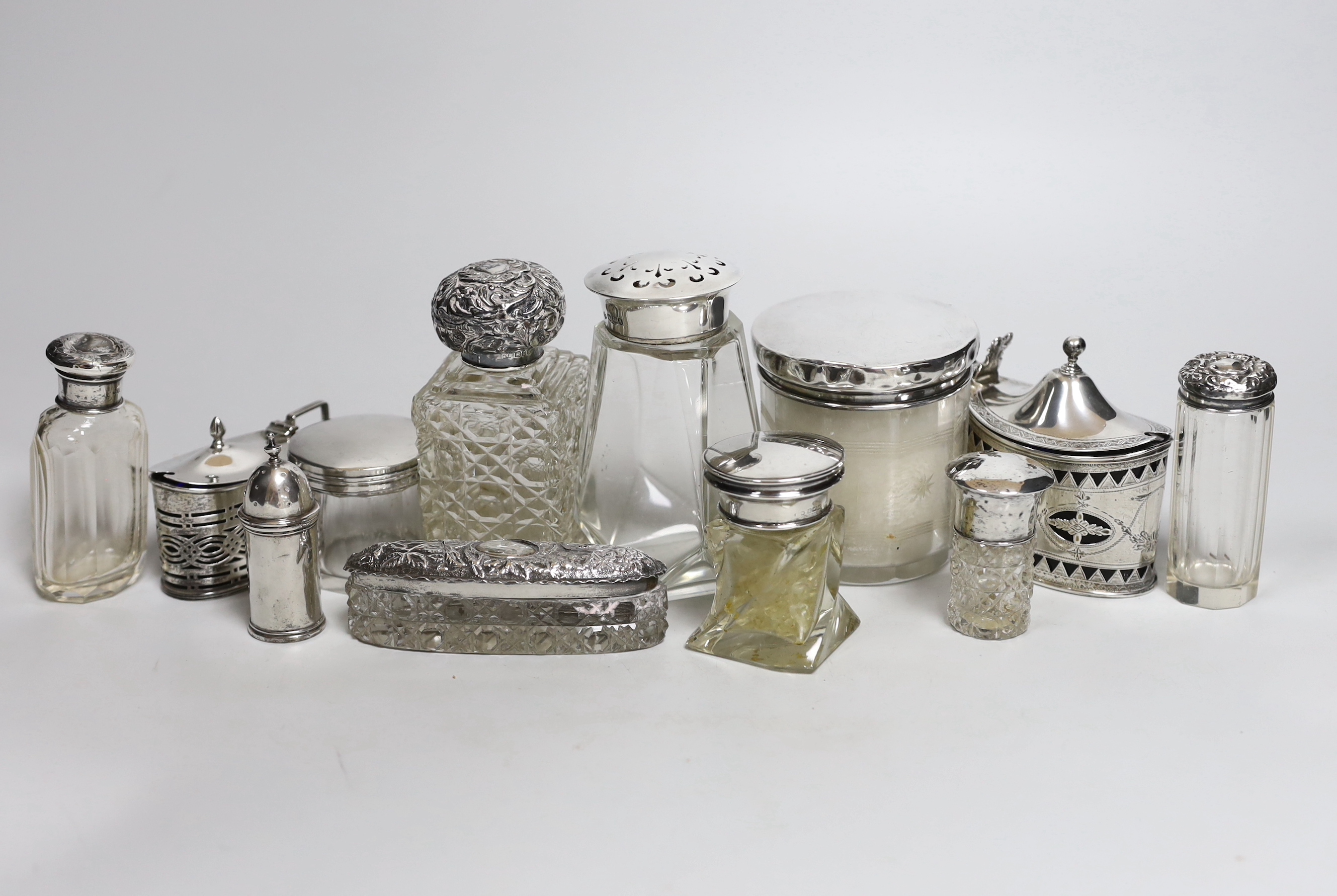 Nine assorted silver mounted glass toilet jars, two mustard pots including largest, London, 1882 and a small silver pepperette.                                                                                             