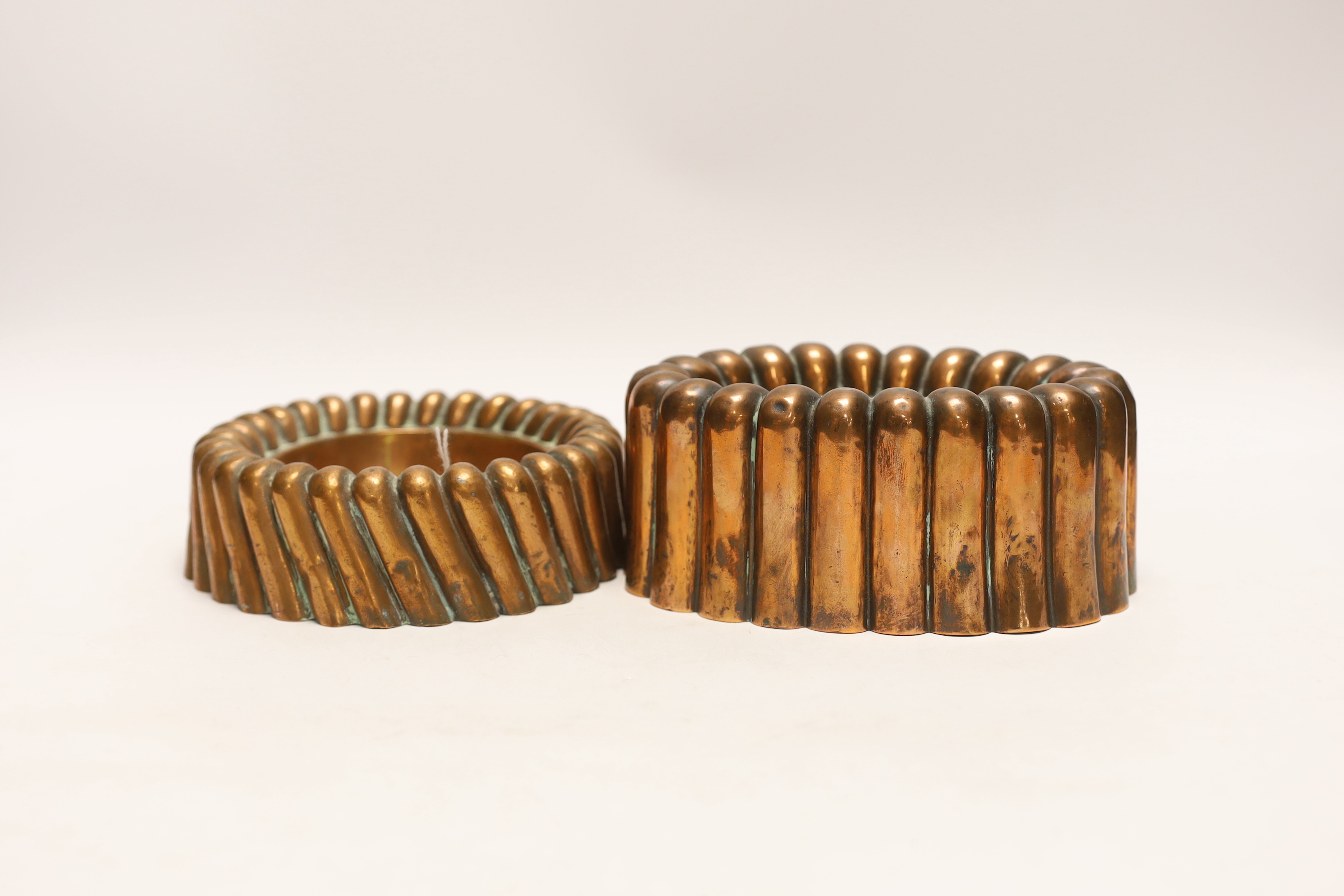 Two Victorian copper jelly moulds, the ring shaped example stamped Baileys hotel and the overall example stamped 64, largest 17cm wide                                                                                      