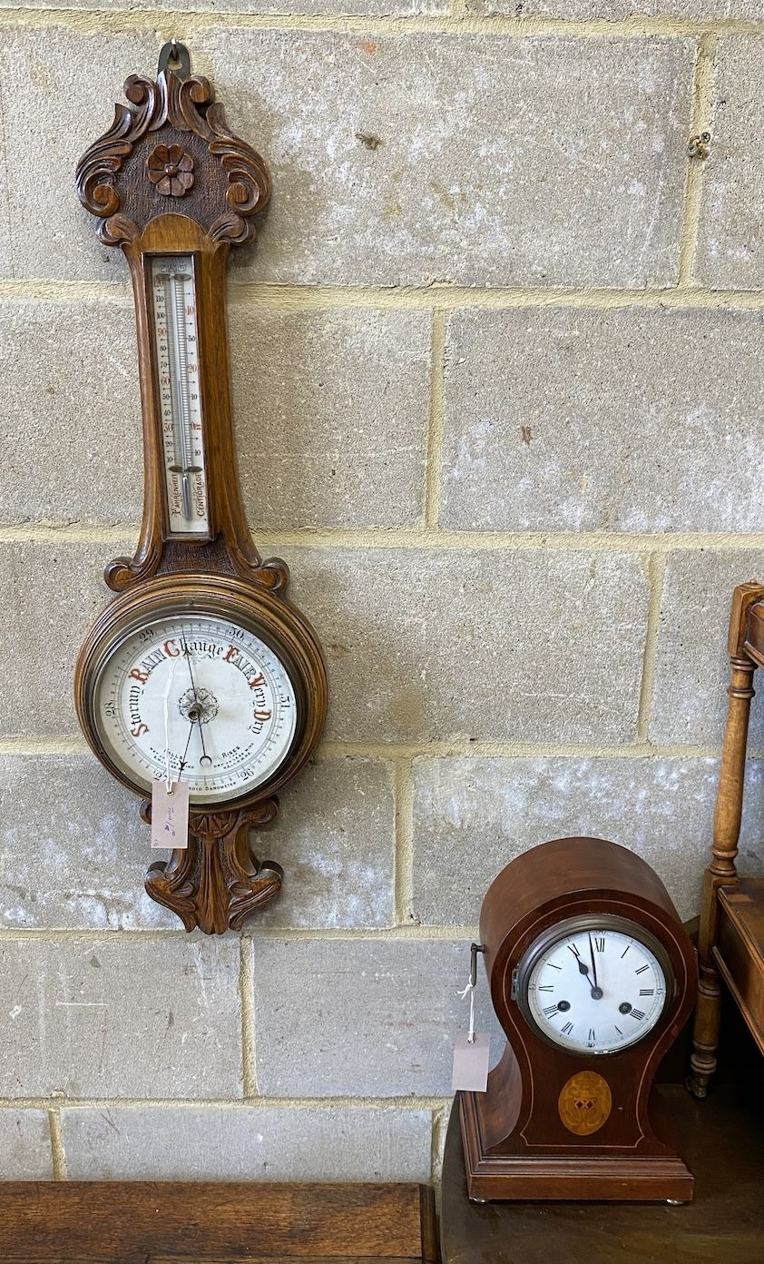 An Edwardian inlaid mahogany tear drop mantel clock, height 34cm and a carved oak aneroid wheel barometer, height 86cm                                                                                                      