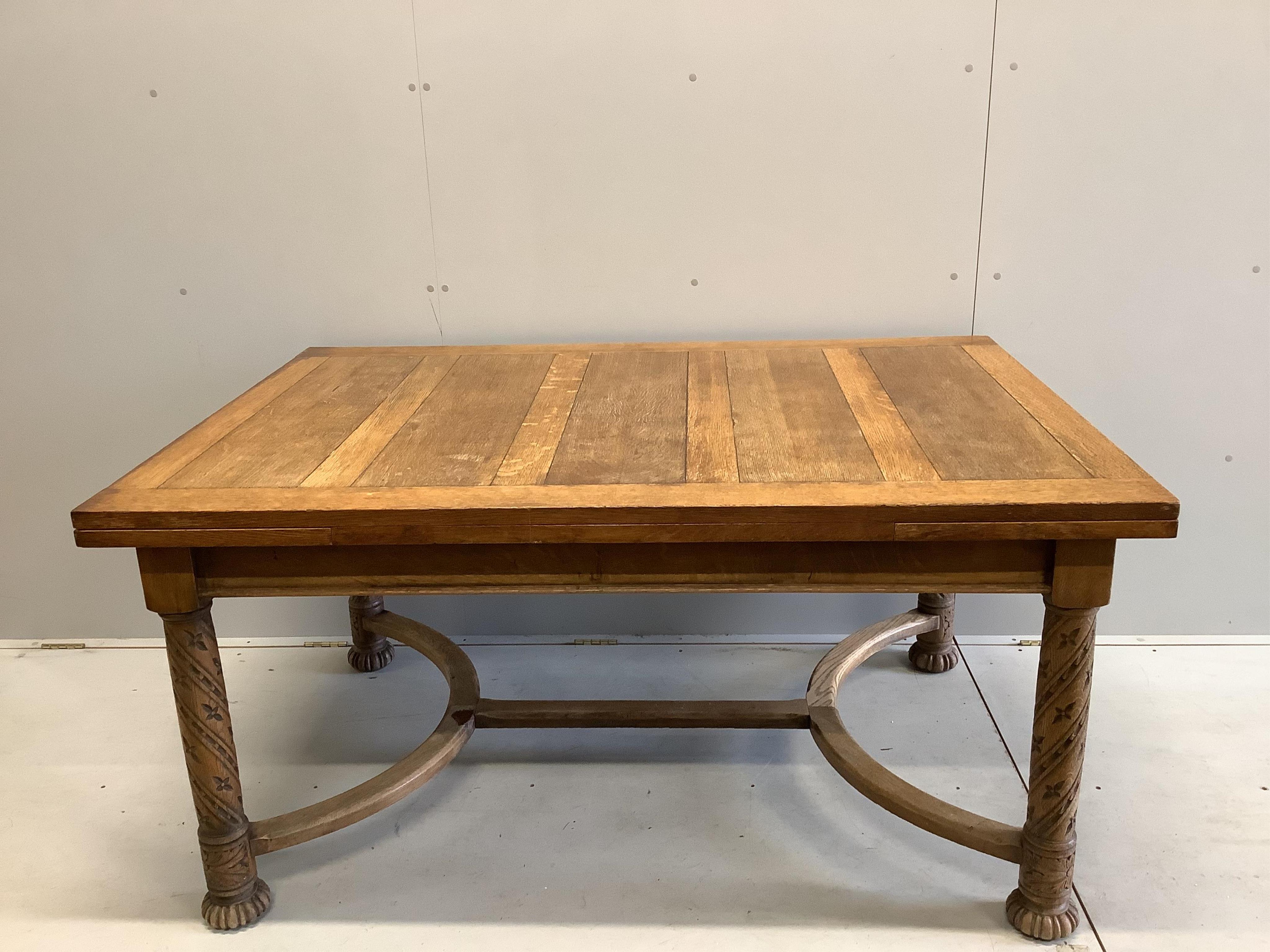 An early 20th century golden oak draw leaf dining table on carved underframe, width 153cm, 227cm extended, depth 106cm, height 76cm. Condition - fair                                                                       