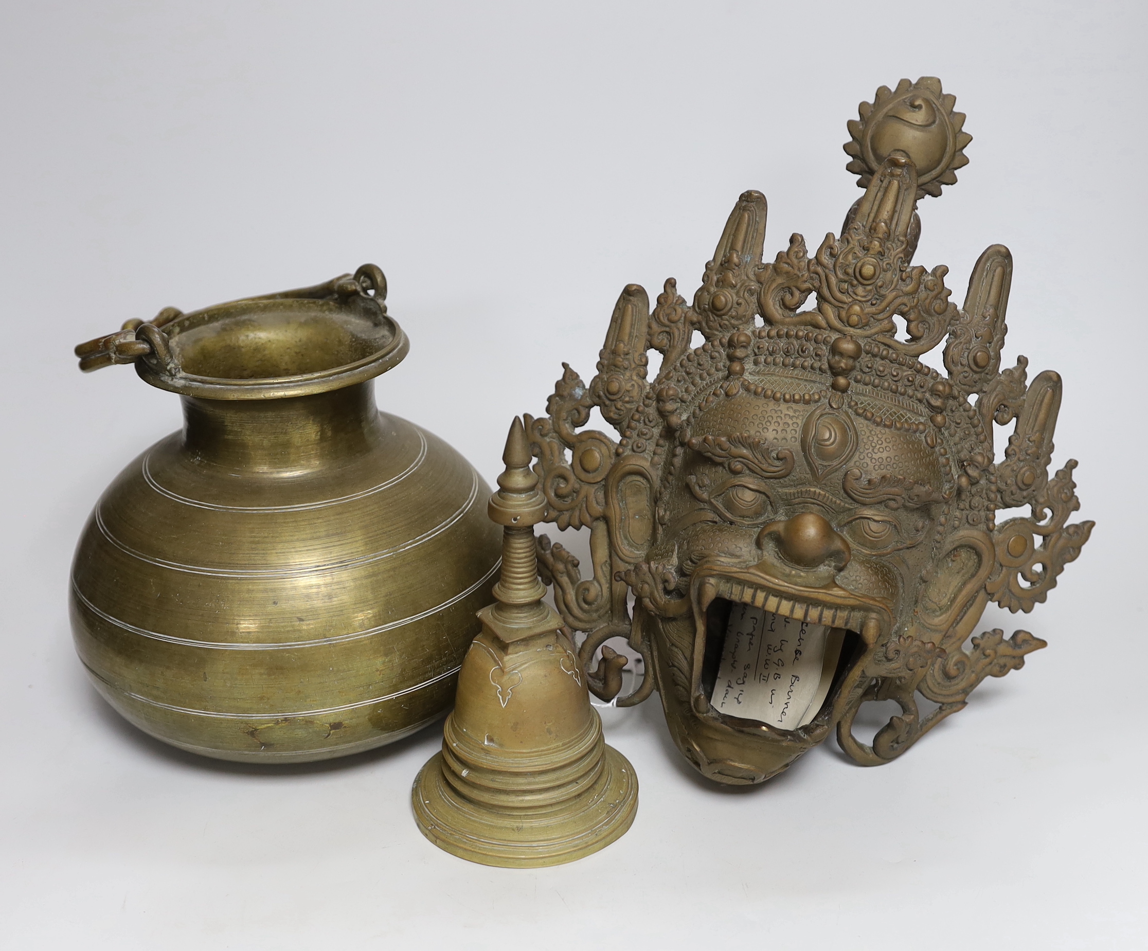 A Tibetan bronze Mahakala mask censer, a stupa shaped bell and a Ceylonese Lota bronze vessel, censer 29cm deep                                                                                                             