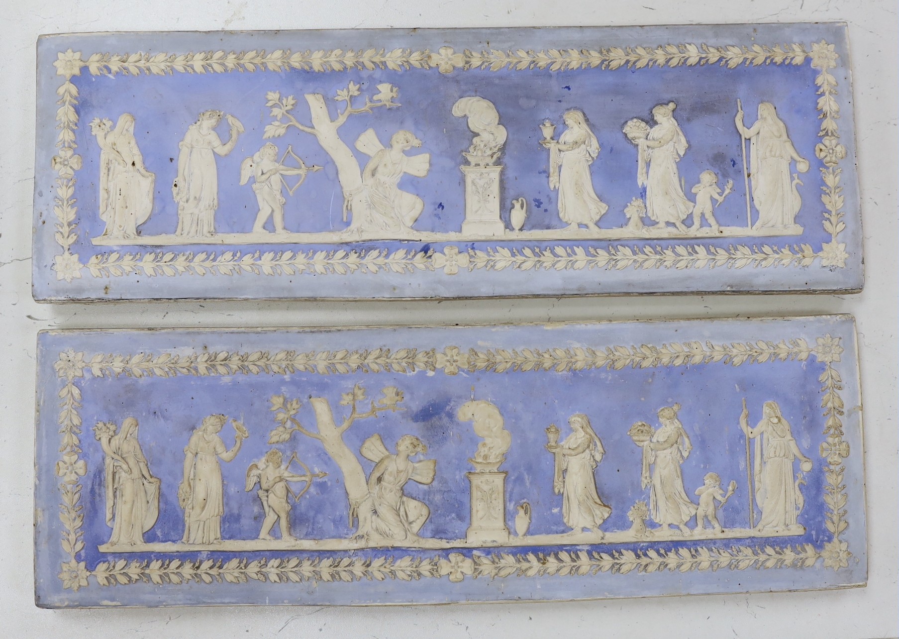 A pair of 19th century blue tinted moulded plaster plaques, imitating Wedgwood jasper ware, 45cms wide x 15 cms                                                                                                             