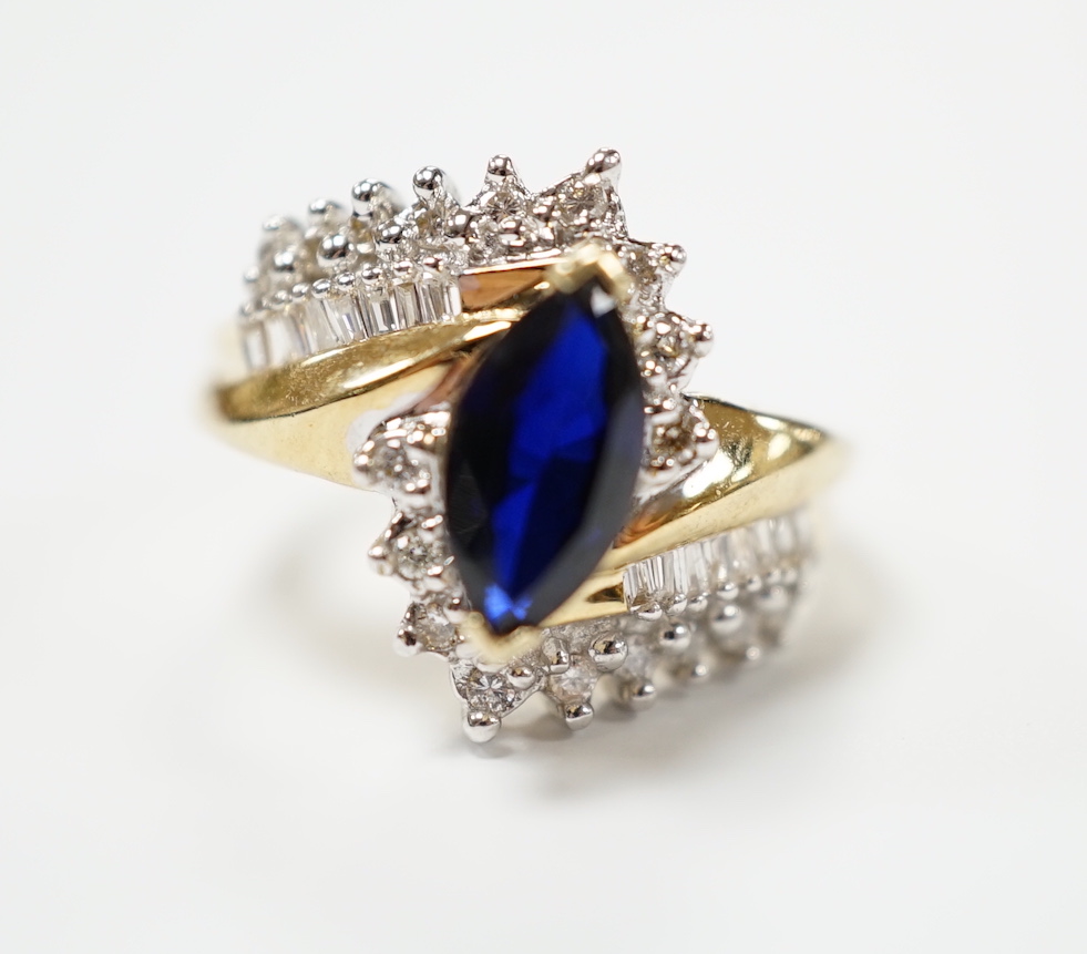 A modern 14k and single stone marquise cut sapphire and diamond chip cluster set crossover dress ring, size M, gross weight 5.3 grams.                                                                                      