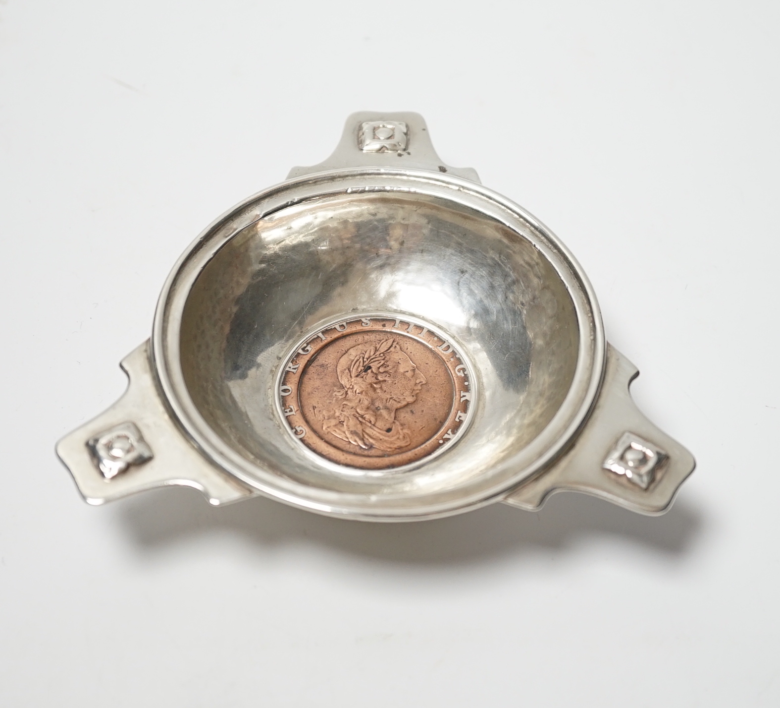 A George V Arts & Craft silver tri-form dish, by Albert Edwards Jones, Birmingham, 1913, the base with inset George III 1797 cartwheel penny, 10.8cm.                                                                       