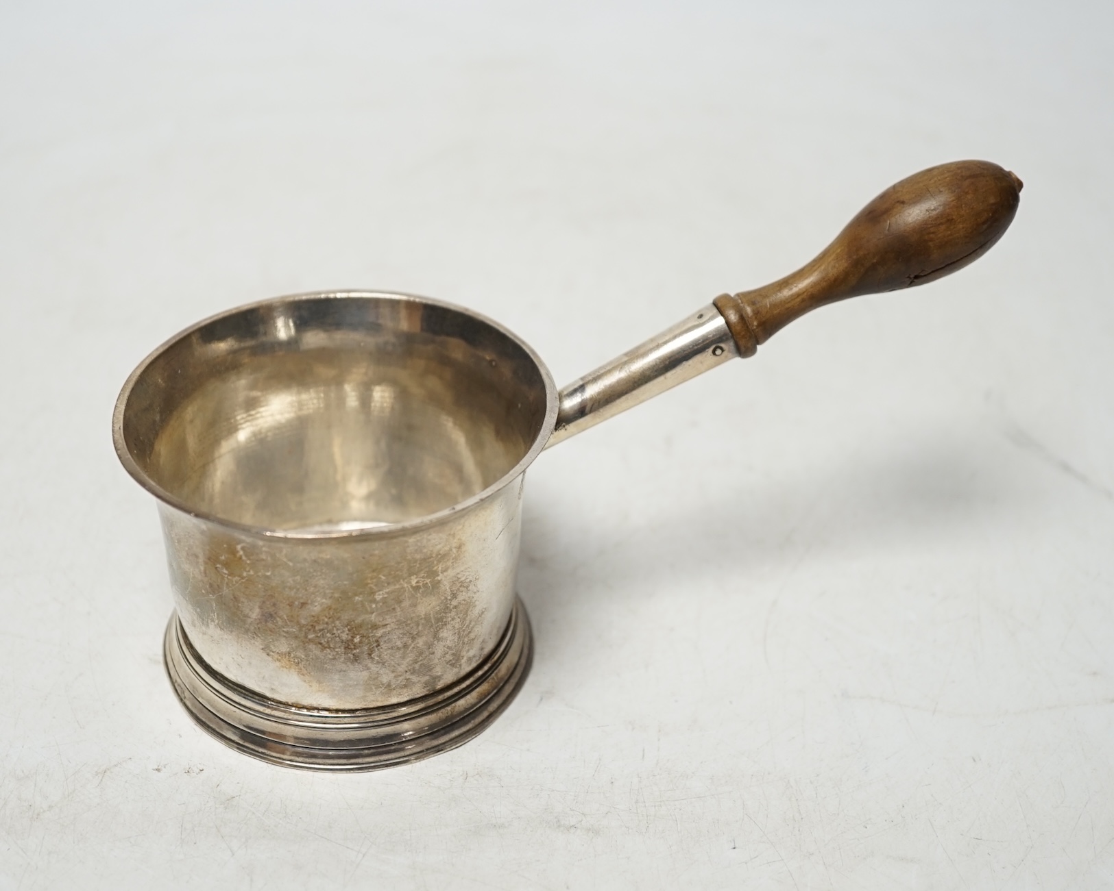 A late 18th/early 19th century silver brandy saucepan, with turned wooden handle, rubbed marks to the base, 17.5cm. Condition - poor                                                                                        