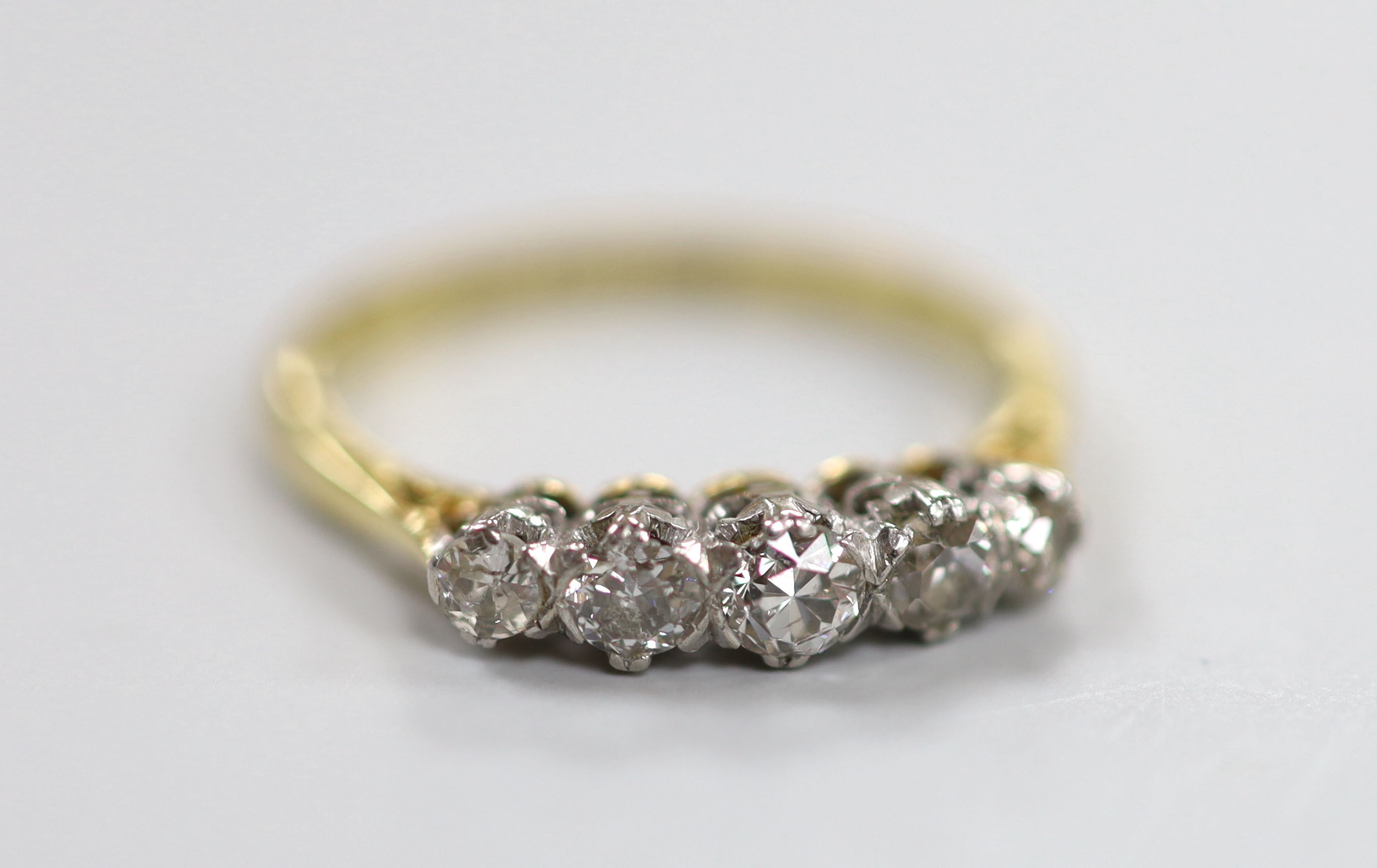 An 18ct, plat and graduated five stone diamond set half hoop ring, size M, gross weight 2.6 grams.                                                                                                                          