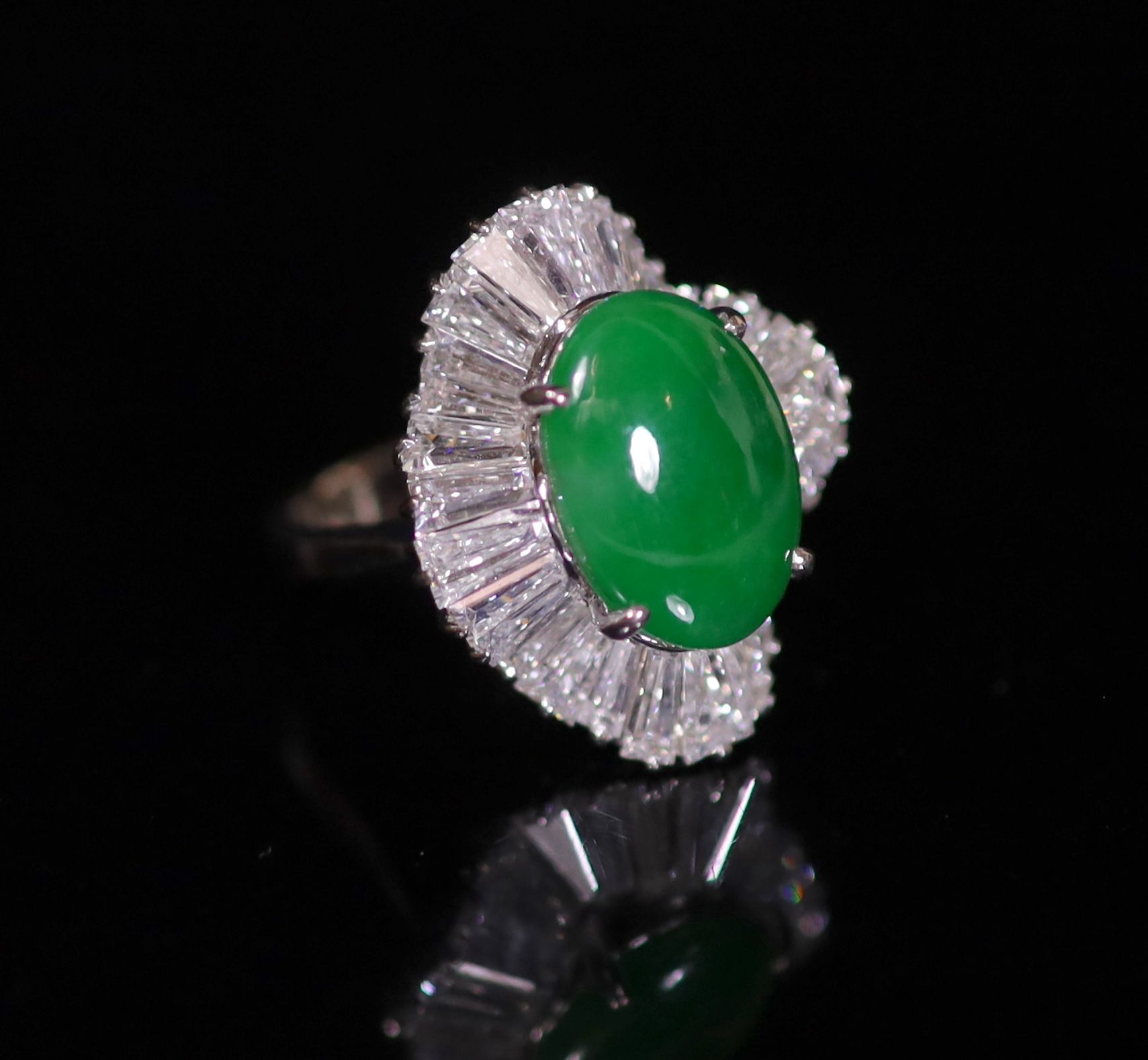 An 18k white gold, green jade and trapeze cut diamond shaped oval 'ballerina' ring, probably Chinese                                                                                                                        