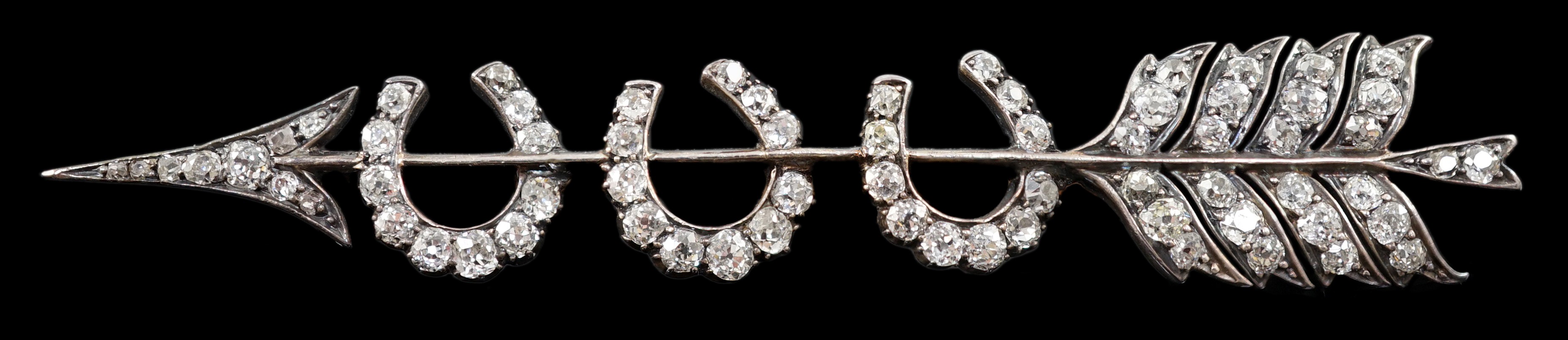 An Edwardian gold, silver and old round cut diamond set gold arrow and triple horseshoe motif set brooch                                                                                                                    