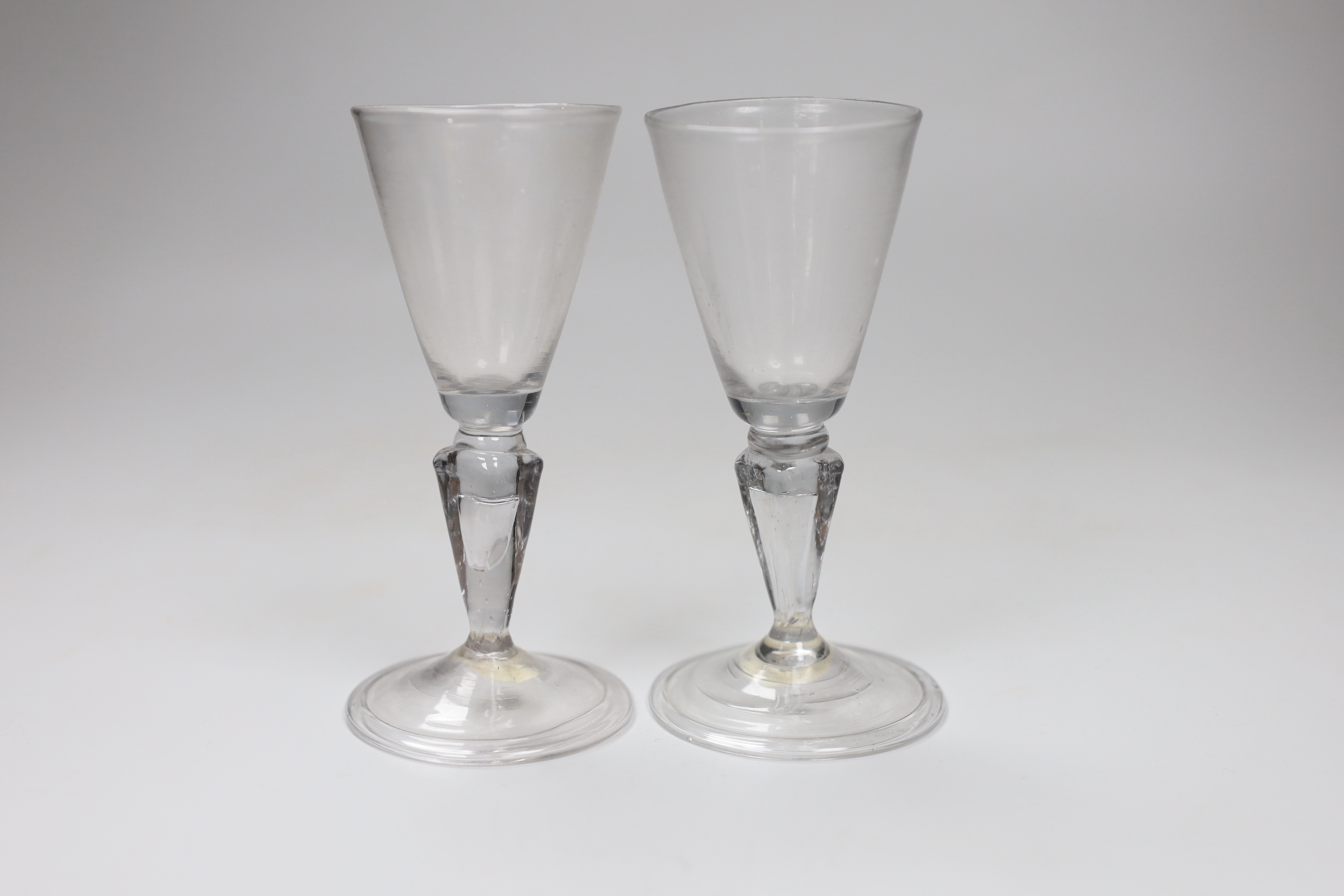 A pair of Continental facon de Venice wine glasses, first half 18th century, round funnel bowls and hollow moulded pedestal stems, folded feet, tallest 13.5cm                                                              