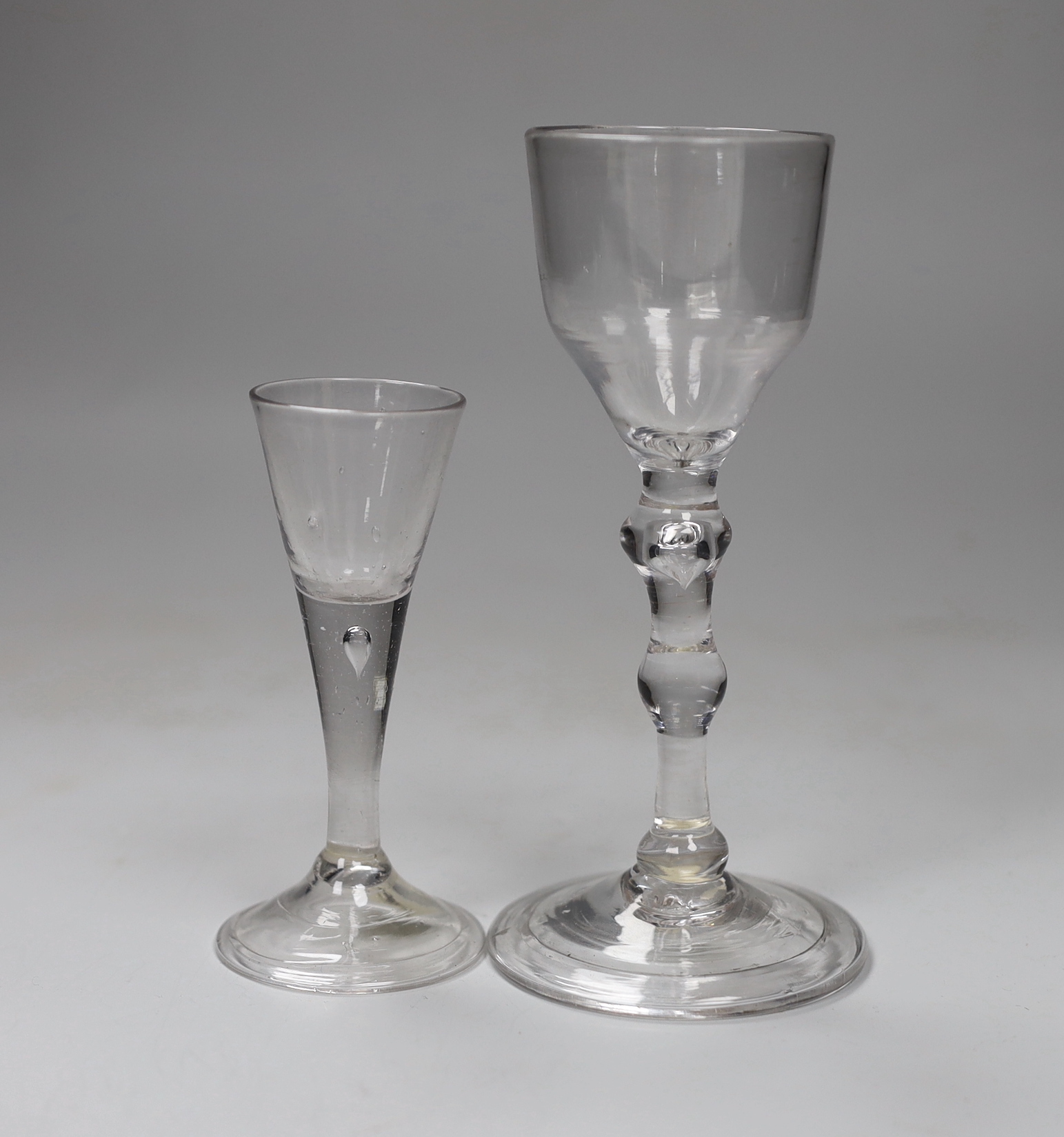 A George II balustroid wine glass, ogee bowl and folded foot, and an unusually small George II cordial or liqueur glass with folded foot, tallest 15cm                                                                      