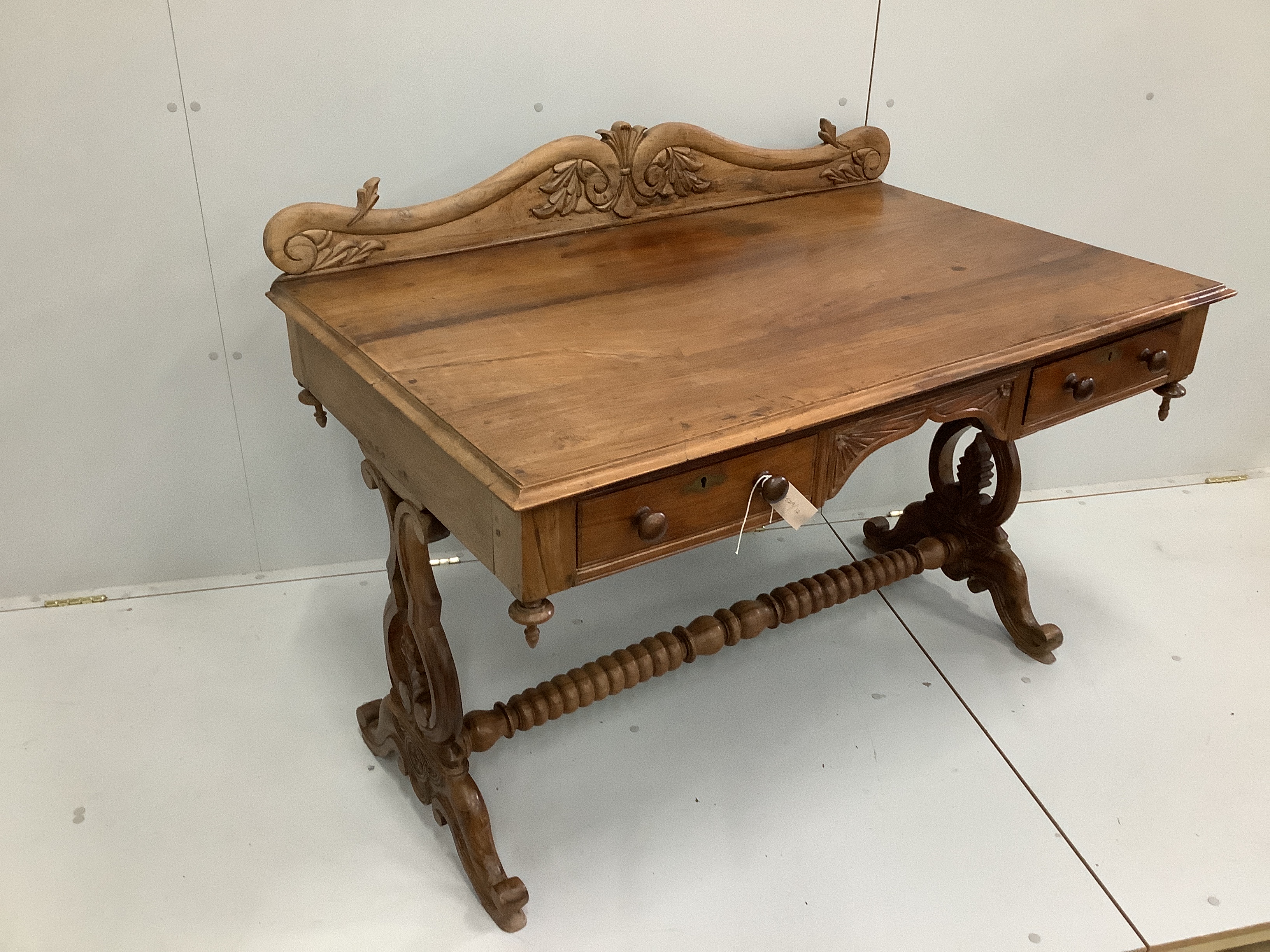An Anglo-Indian carved hardwood writing table, two frieze drawers, on scrolled end supports, width 121cm. depth 74cm, height 92cm                                                                                           