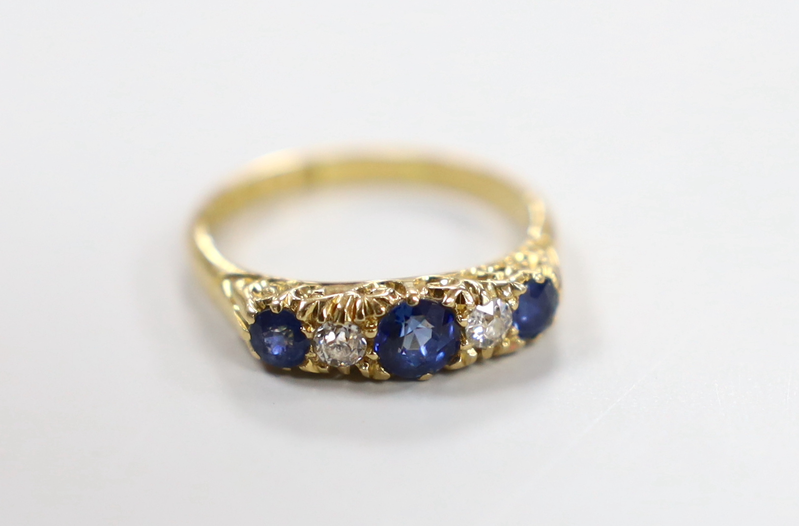 A late Victorian 18ct gold, three stone sapphire and two stone diamond set half hoop ring, size P, gross weight 3.8 grams.                                                                                                  